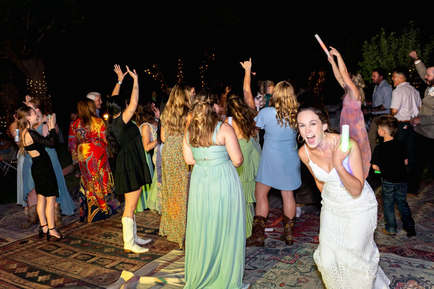 Wedding guests dancing and celebrating on outdoor patio at night reception.