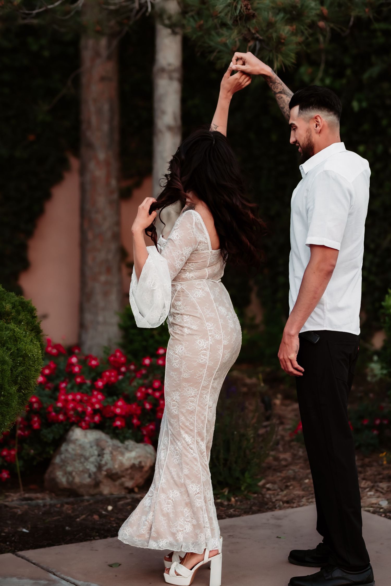 A romantic dance pose of a couple with the woman in a lace dress and man in white shirt.