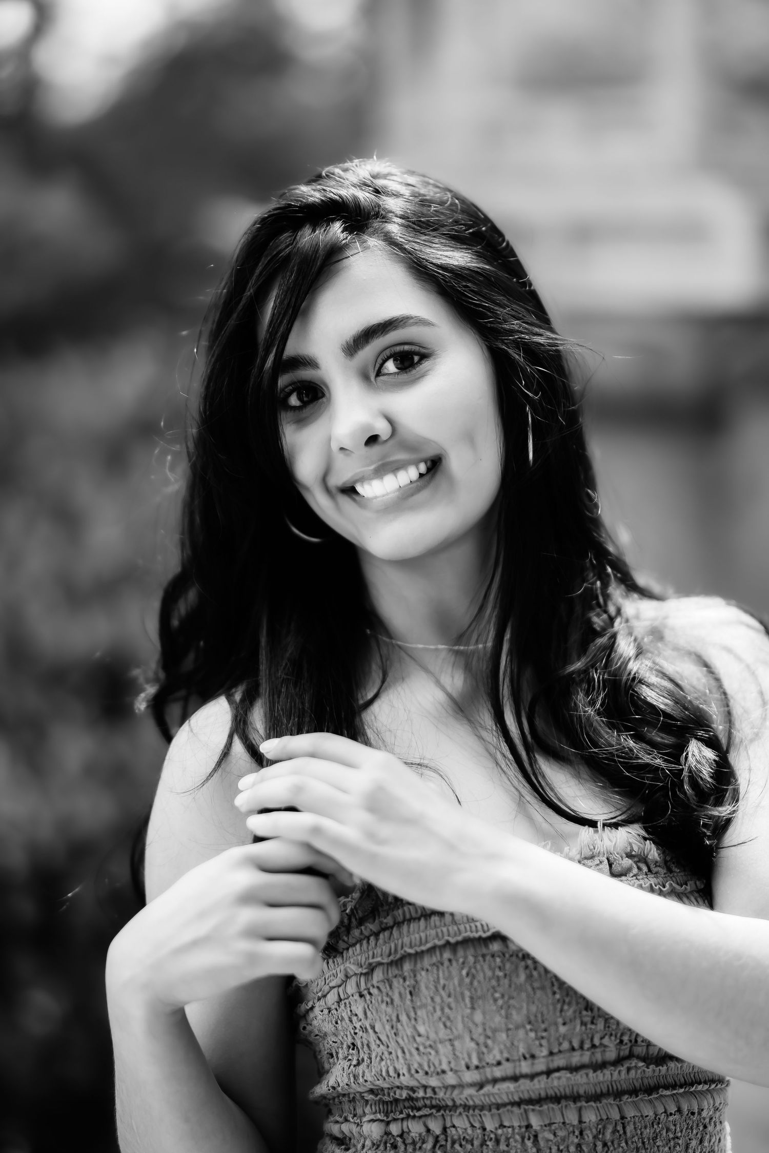 Black and white closeup portrait of woman with long dark hair and natural smile.