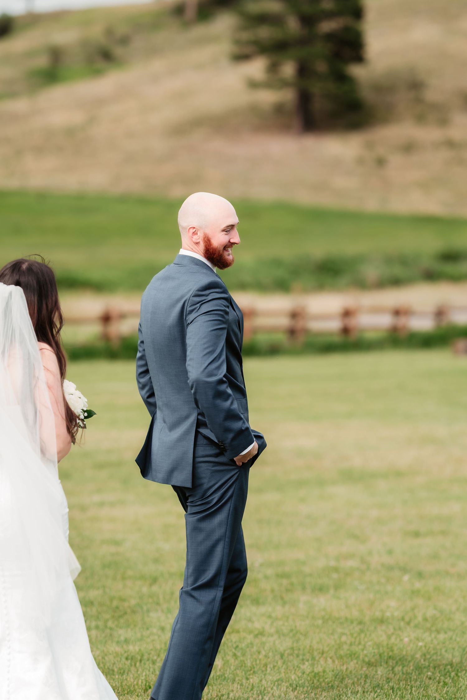 A romantic first look sequence in a grassy field with mountains in the background during a wedding celebration.