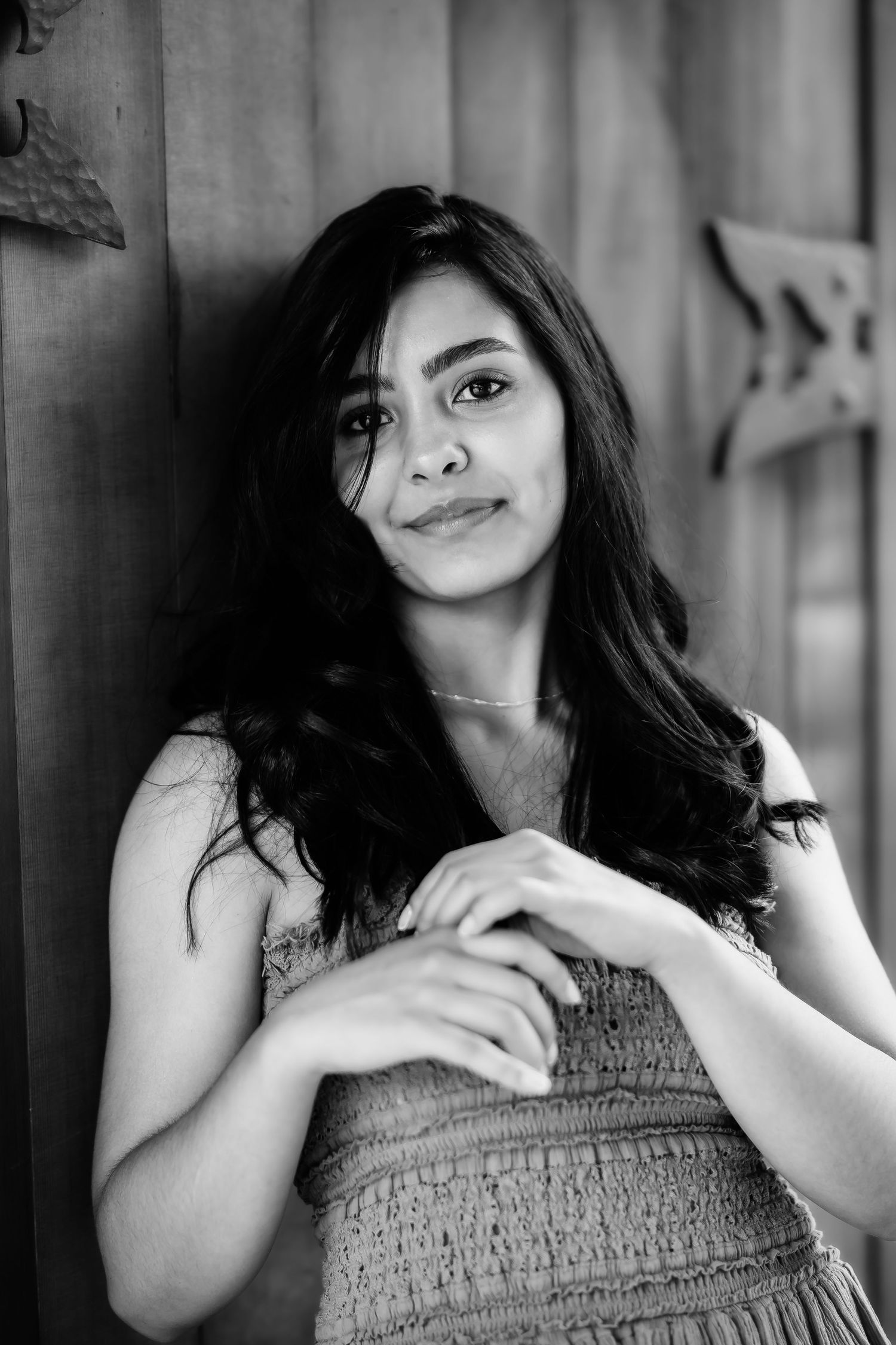 A black and white portrait leaning against a wall in a textured sleeveless top.