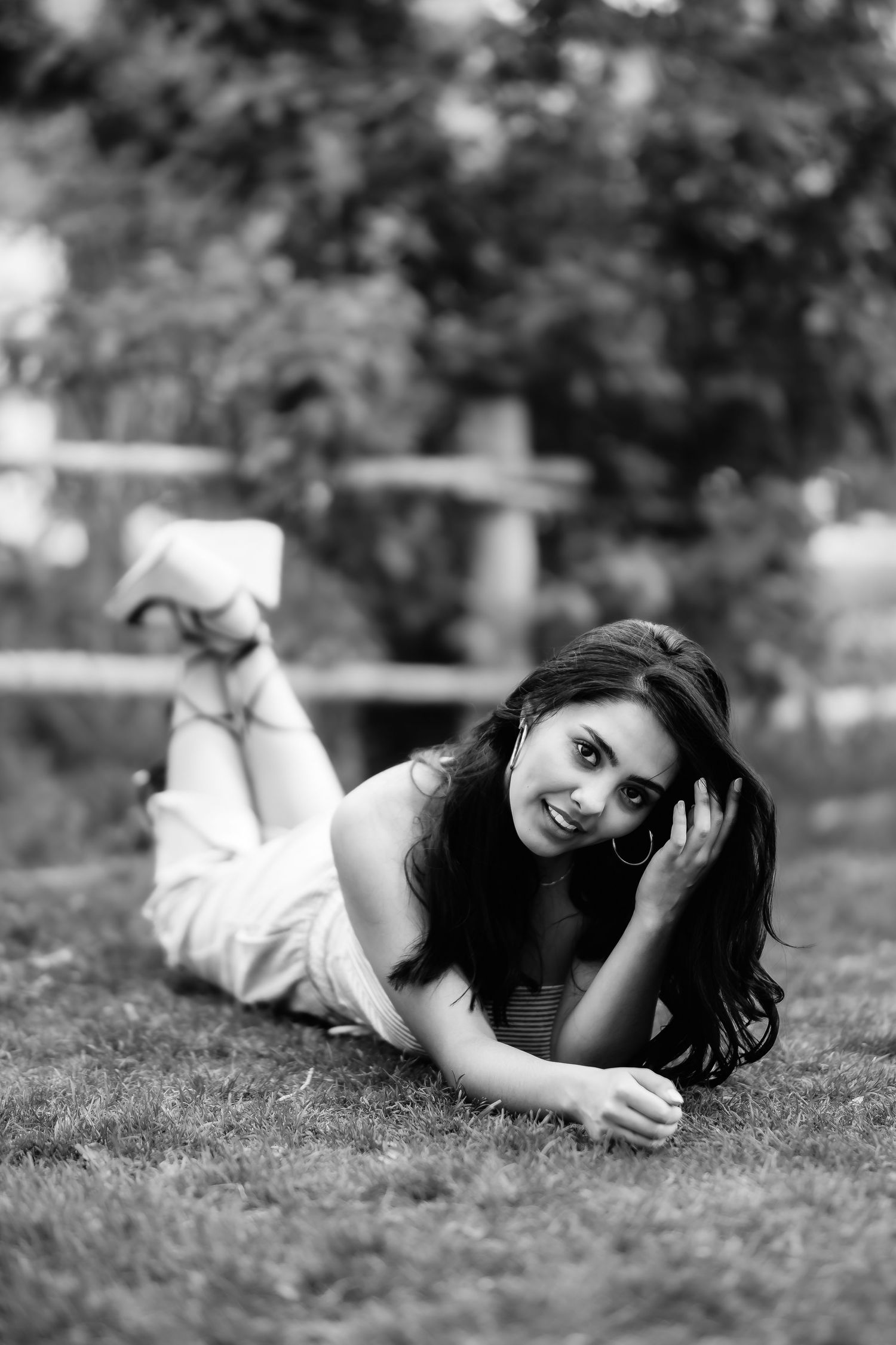 Black and white photo of a person lying on grass in casual attire with relaxed, natural pose.
