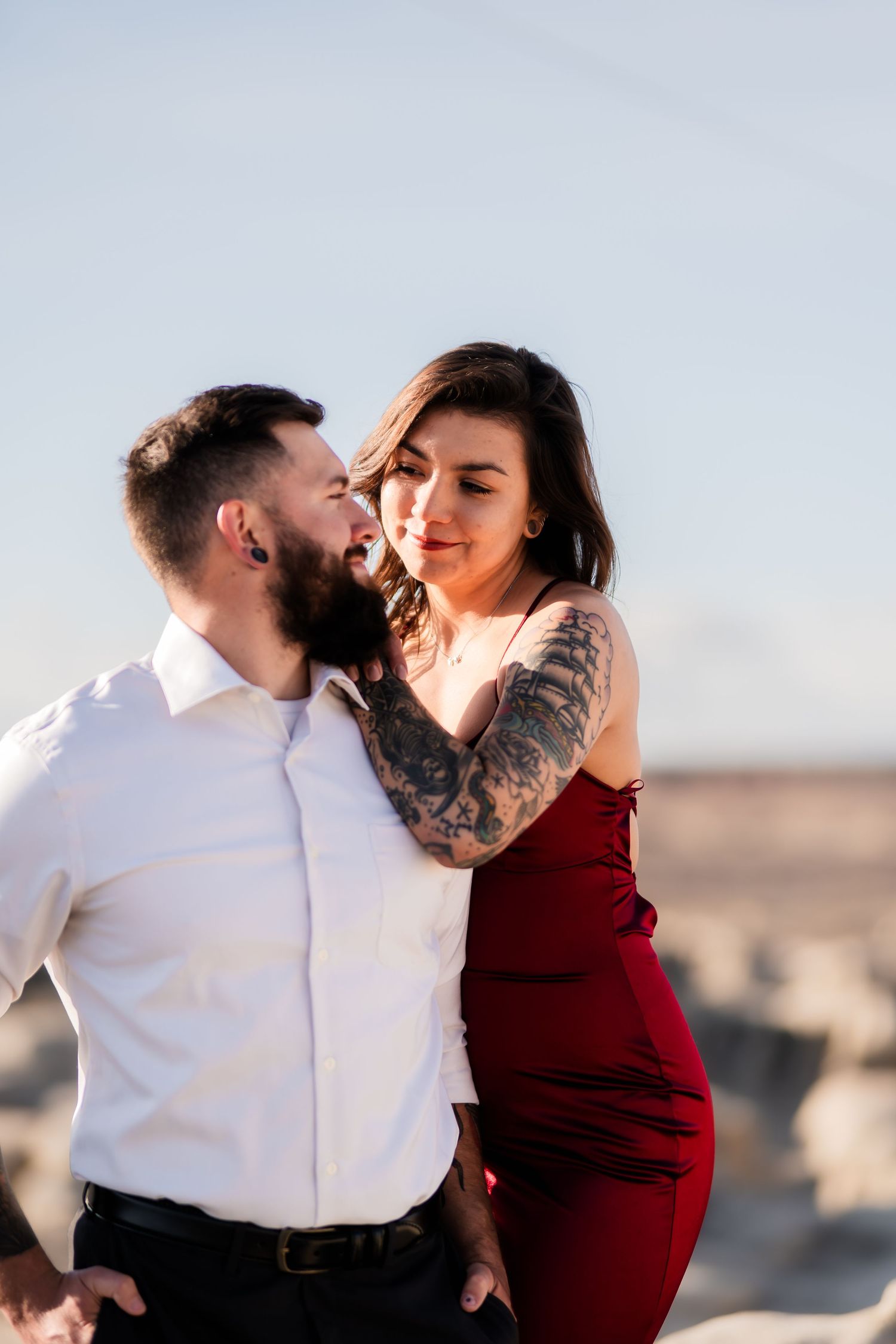 A romantic moment between two people in formal attire against a desert landscape.