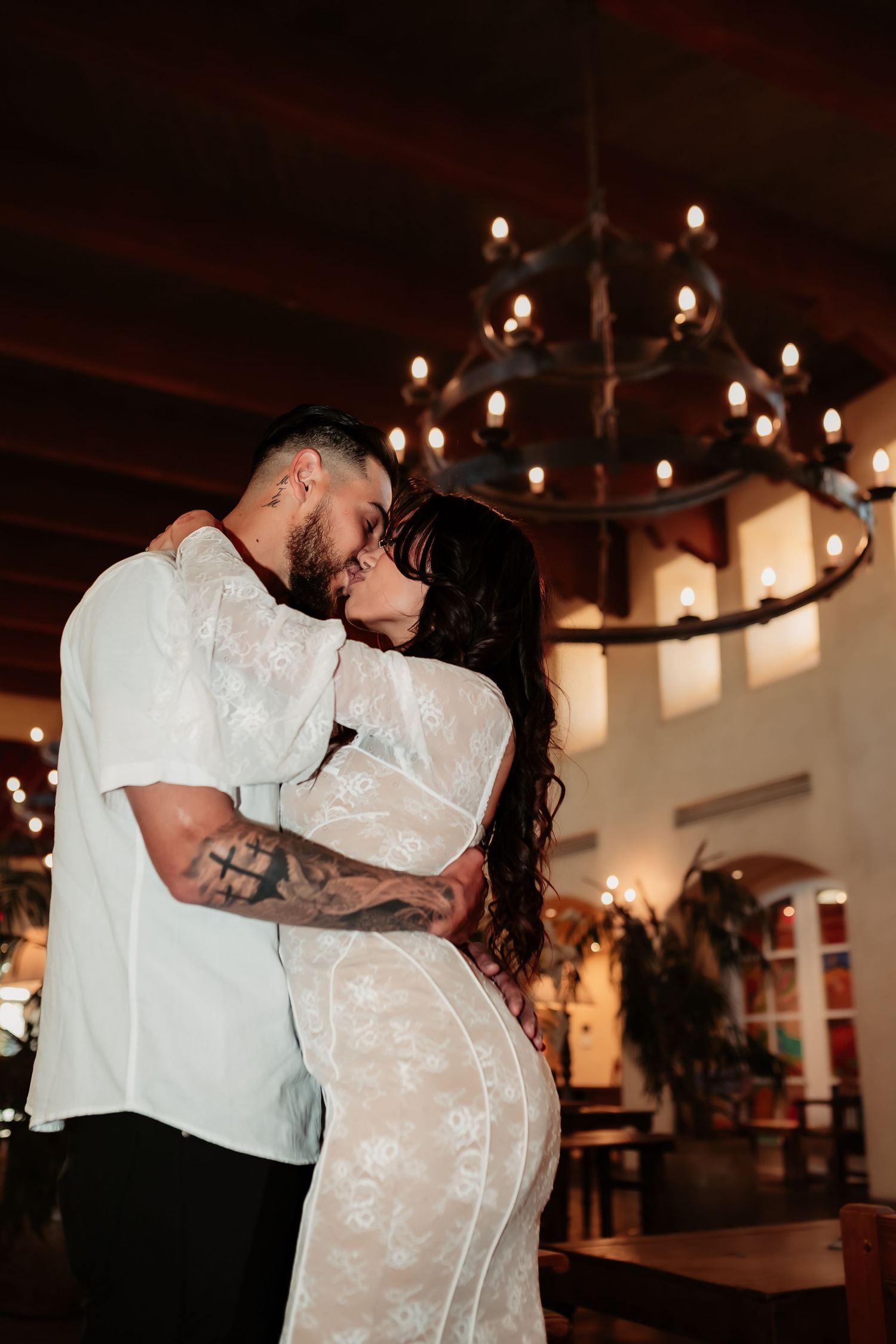 Couple sharing romantic moment under chandelier in elegant venue.