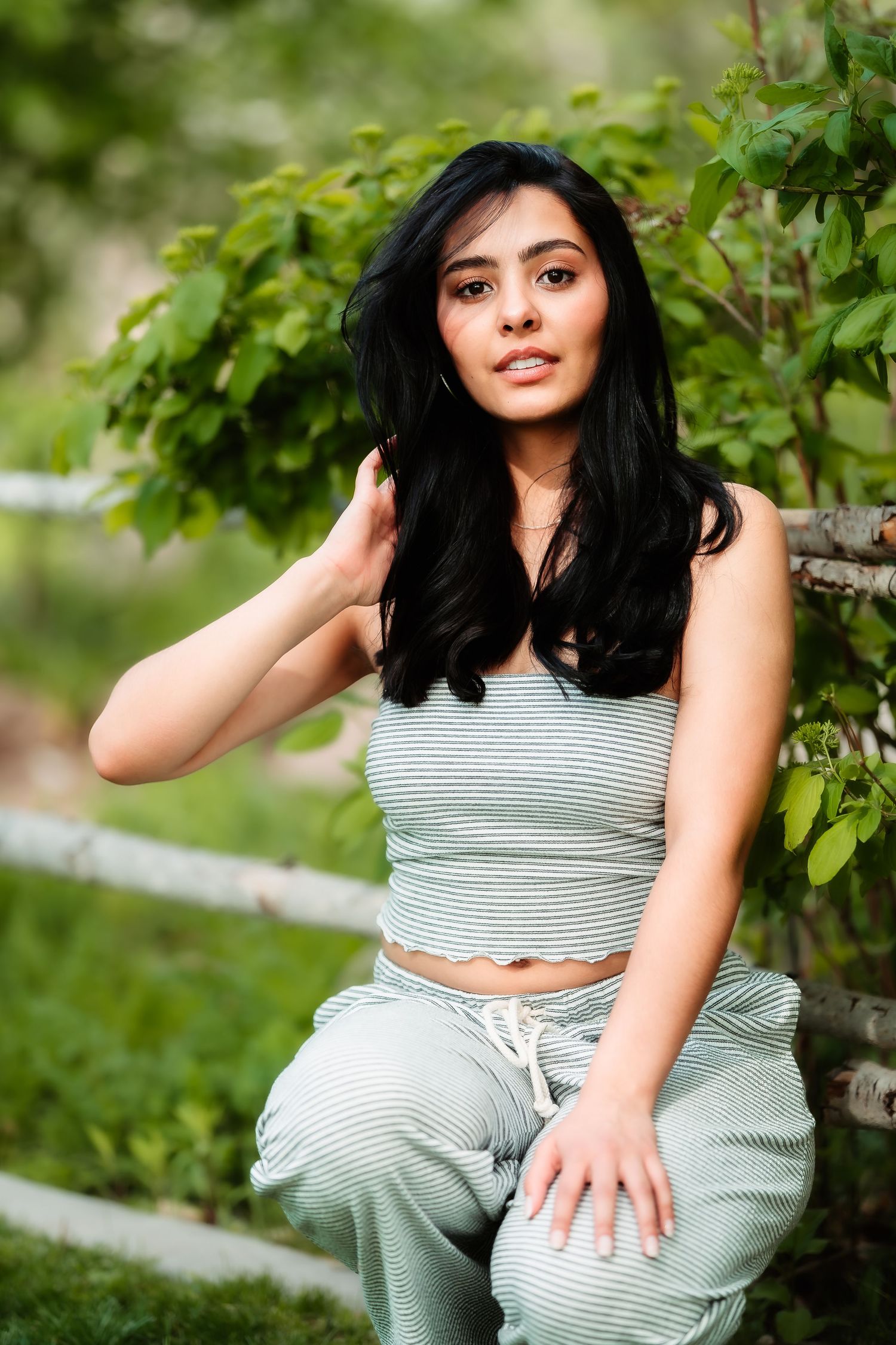 Casual outdoor photoshoot featuring a grey striped crop top and matching pants amid lush greenery.