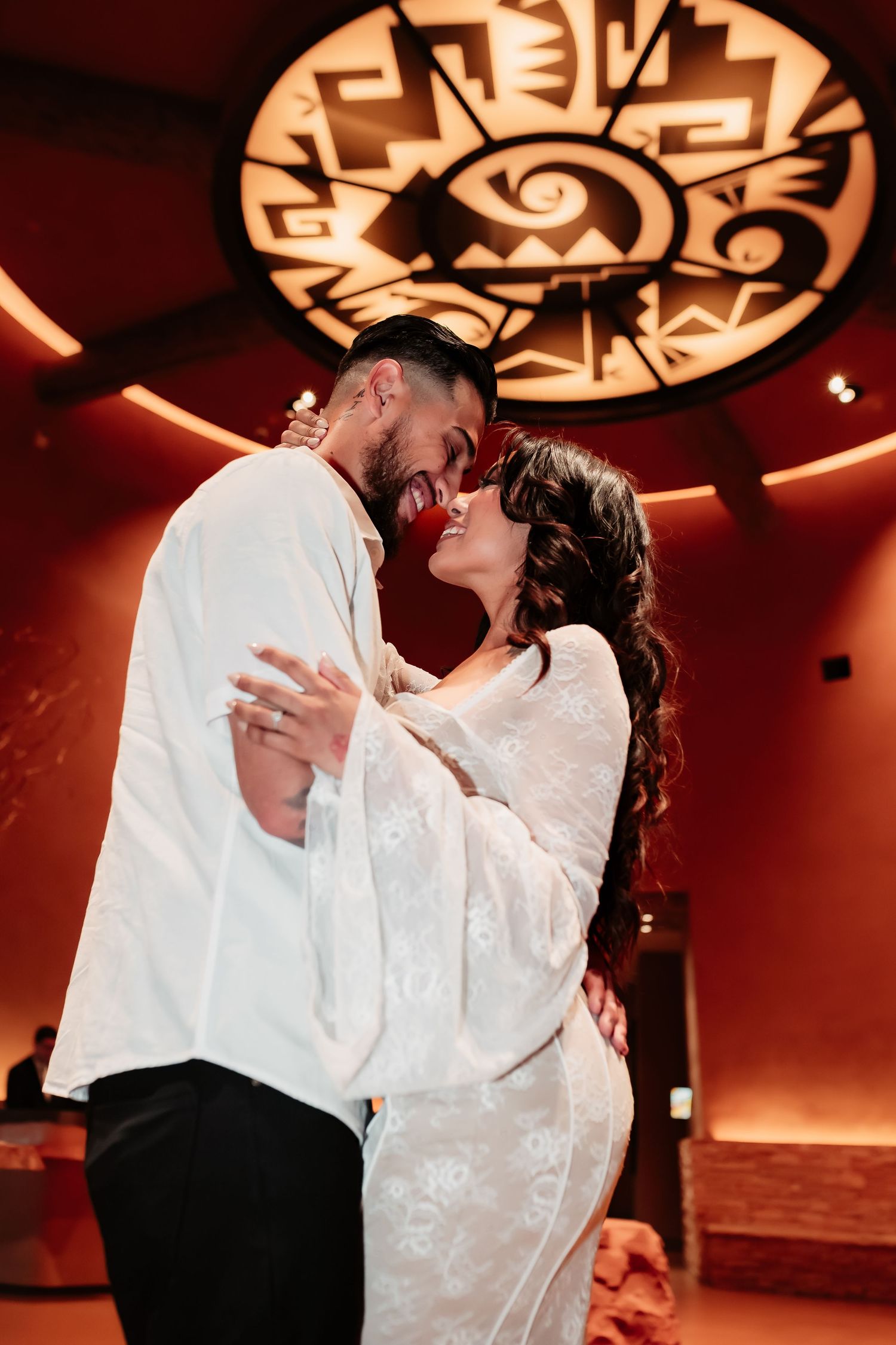 A couple shares an intimate moment on the dance floor under a dramatic southwestern-style ceiling medallion.