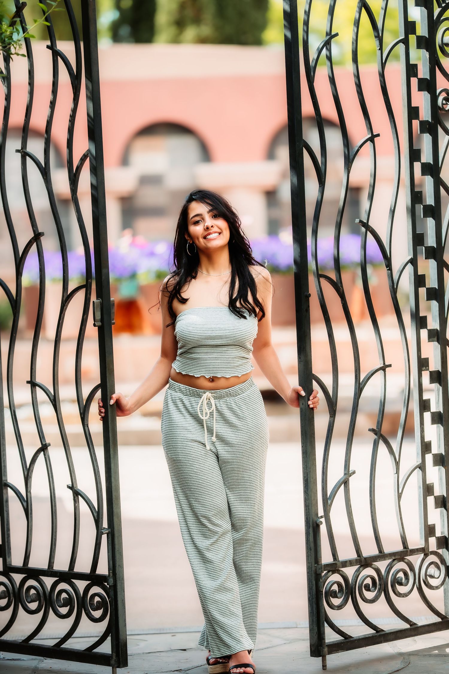 A person stands between decorative iron gates wearing casual loungewear.