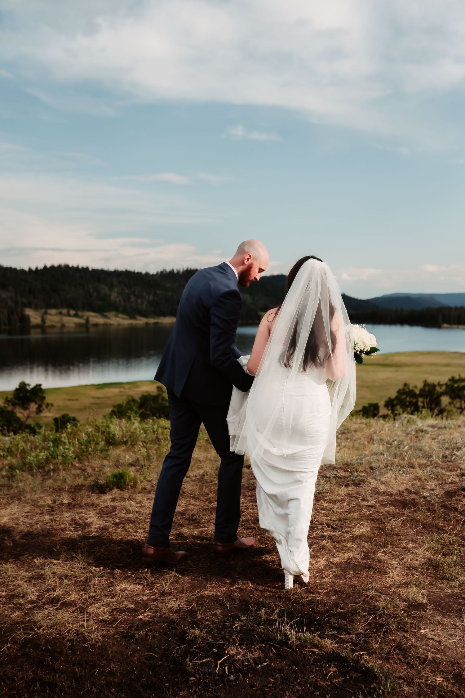 A wedding photo sequence showing a couple walking along a scenic overlook with a lake view.