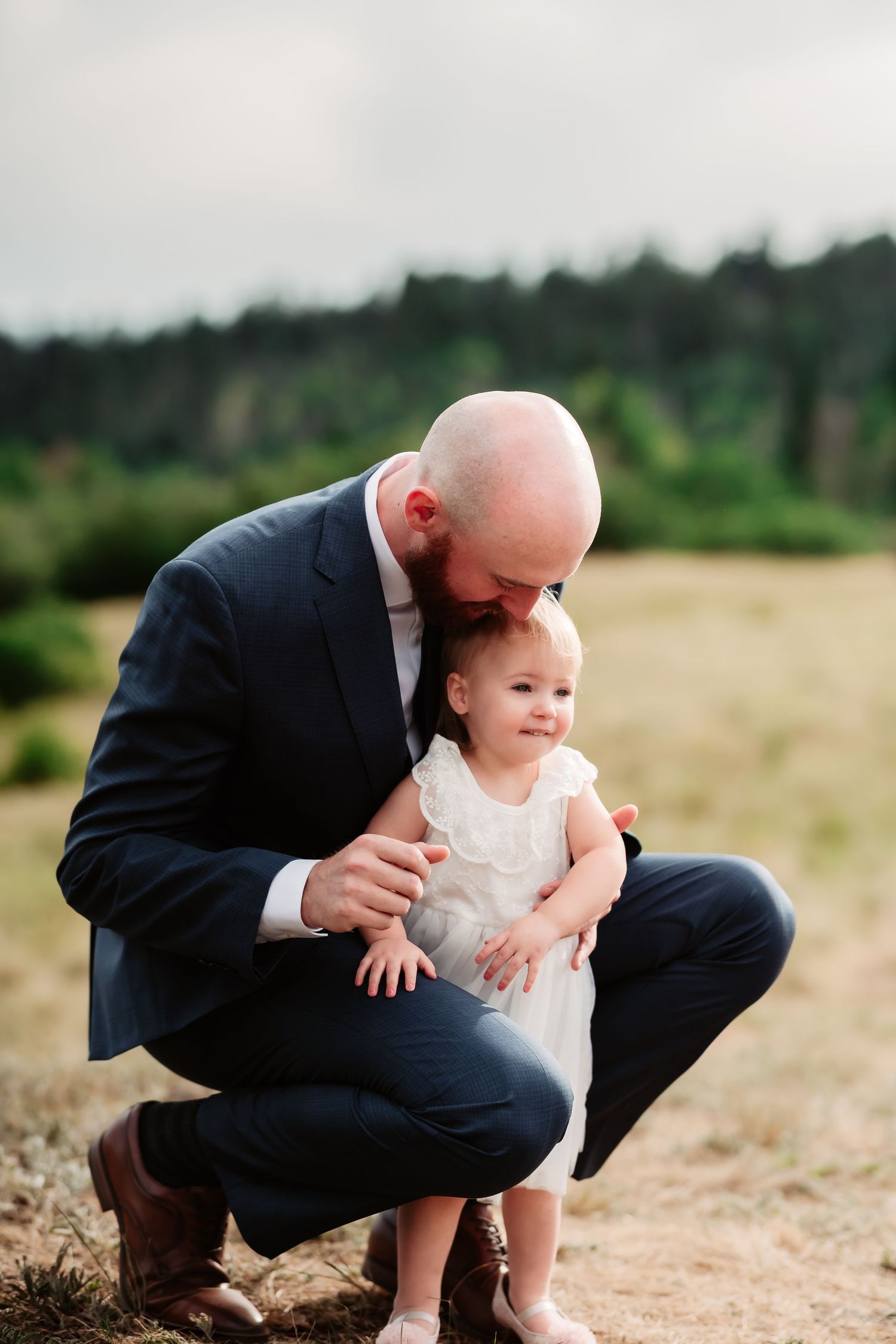 Tender interaction with small child in white dress on outdoor mountain trail.