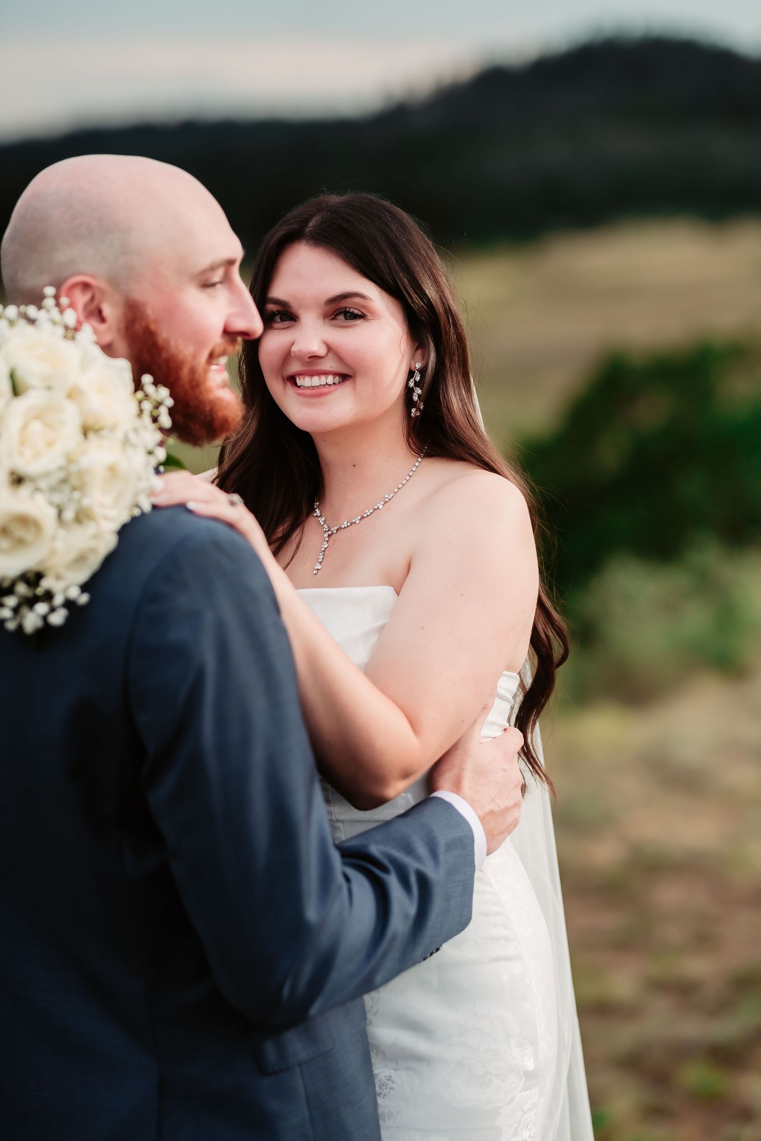 Romantic wedding portraits captured against mountainous backdrop during outdoor ceremony.
