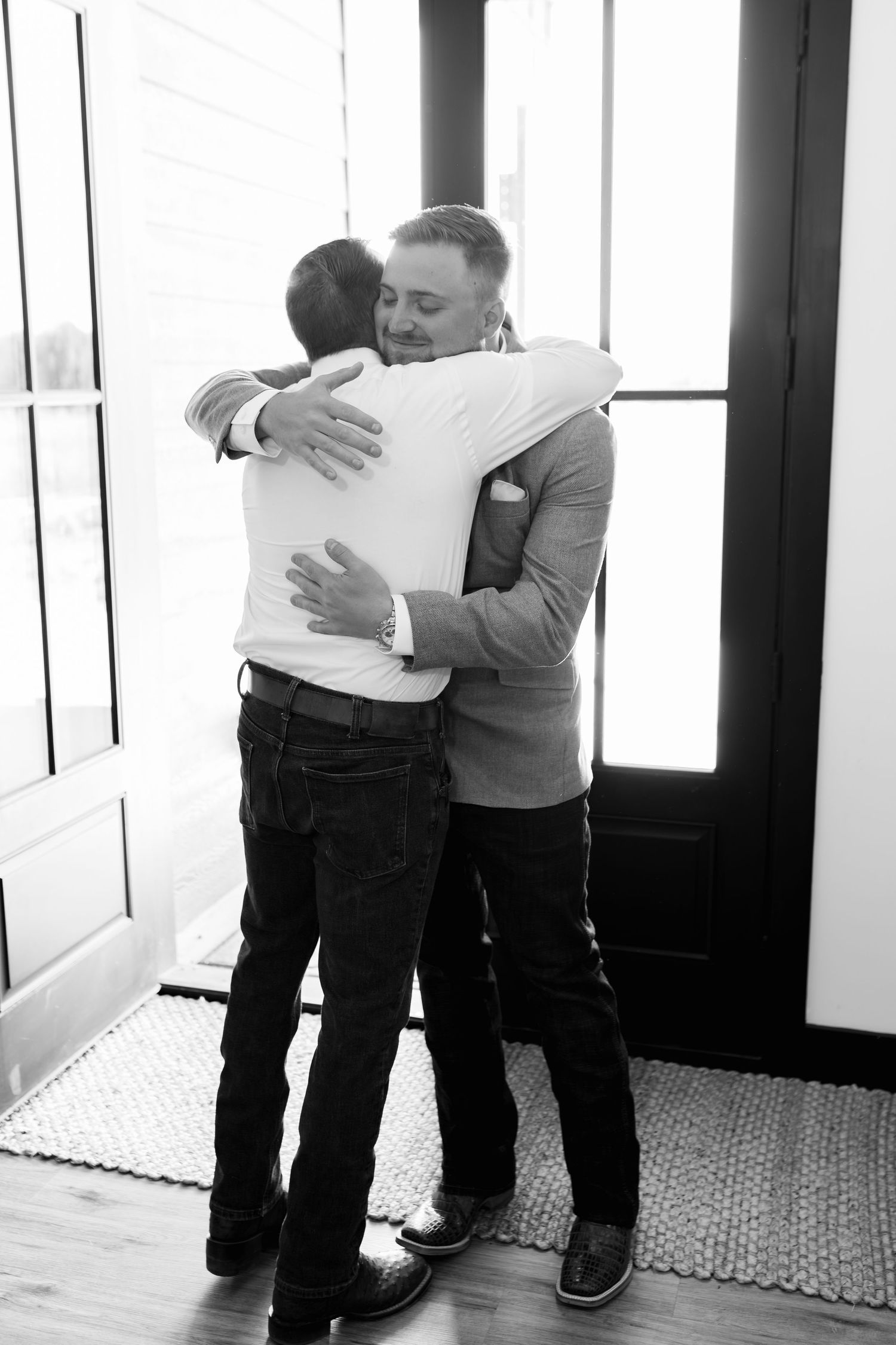 An emotional black and white moment of two people sharing a heartfelt embrace indoors.