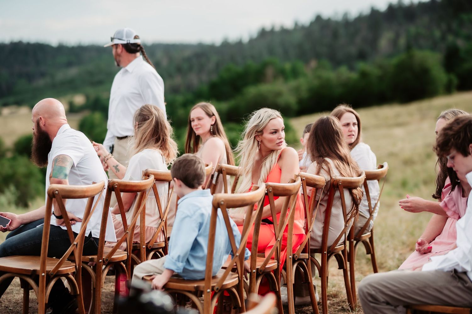 Row of wooden chairs set up for outdoor wedding ceremony with mountain views.