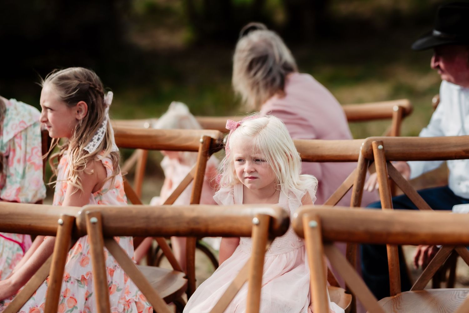 Outdoor wedding ceremony showing rows of wooden chairs with guests seated.