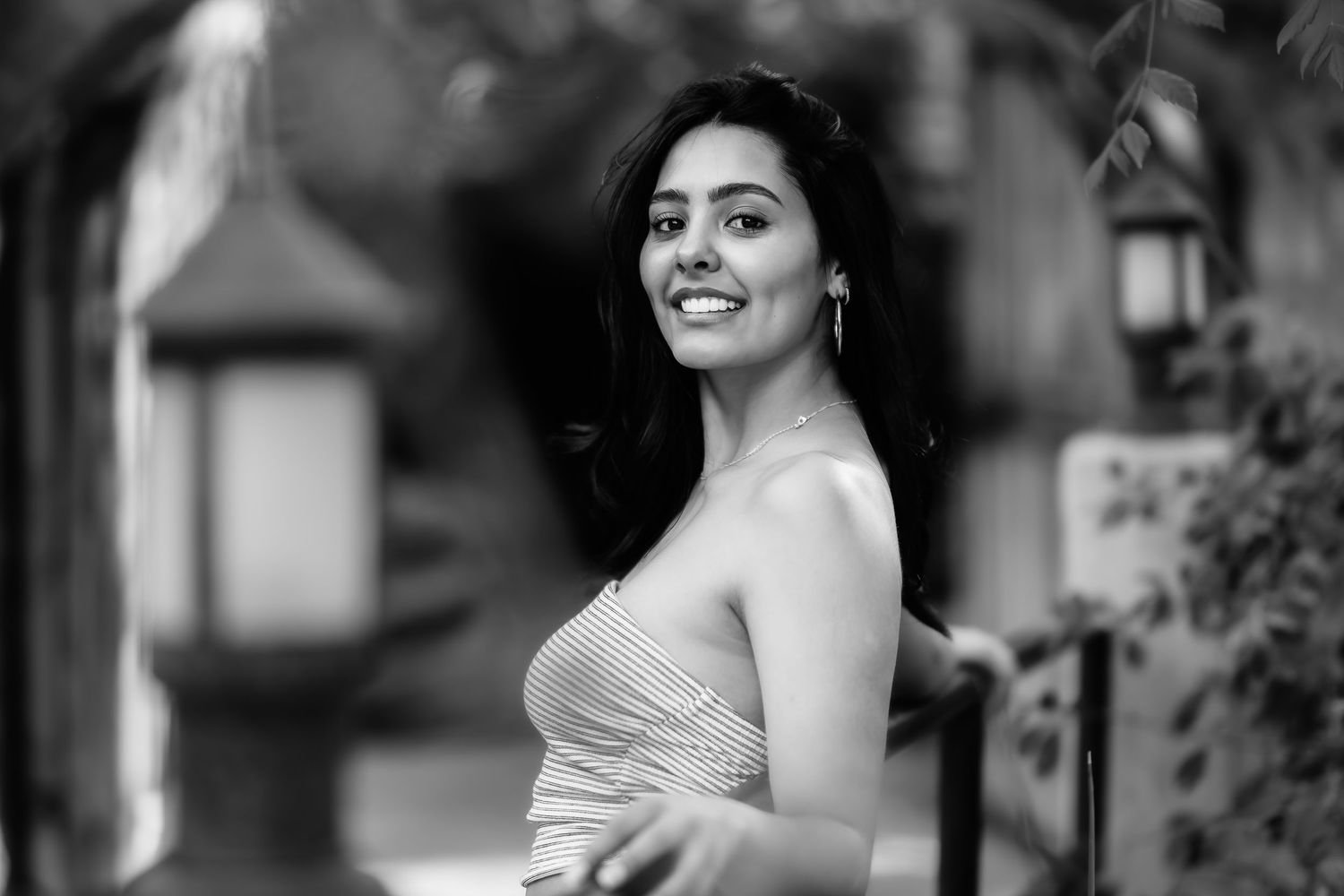 A black and white close-up portrait captures someone smiling warmly in outdoor lighting.