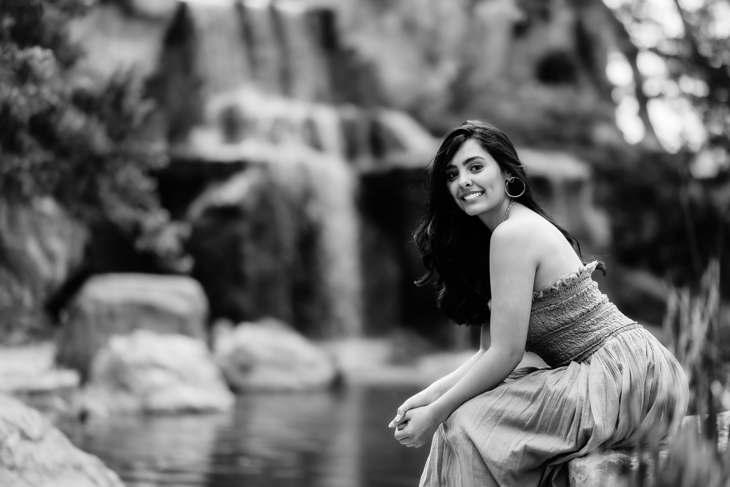 A monochrome portrait showing a relaxed pose near a cascading waterfall.