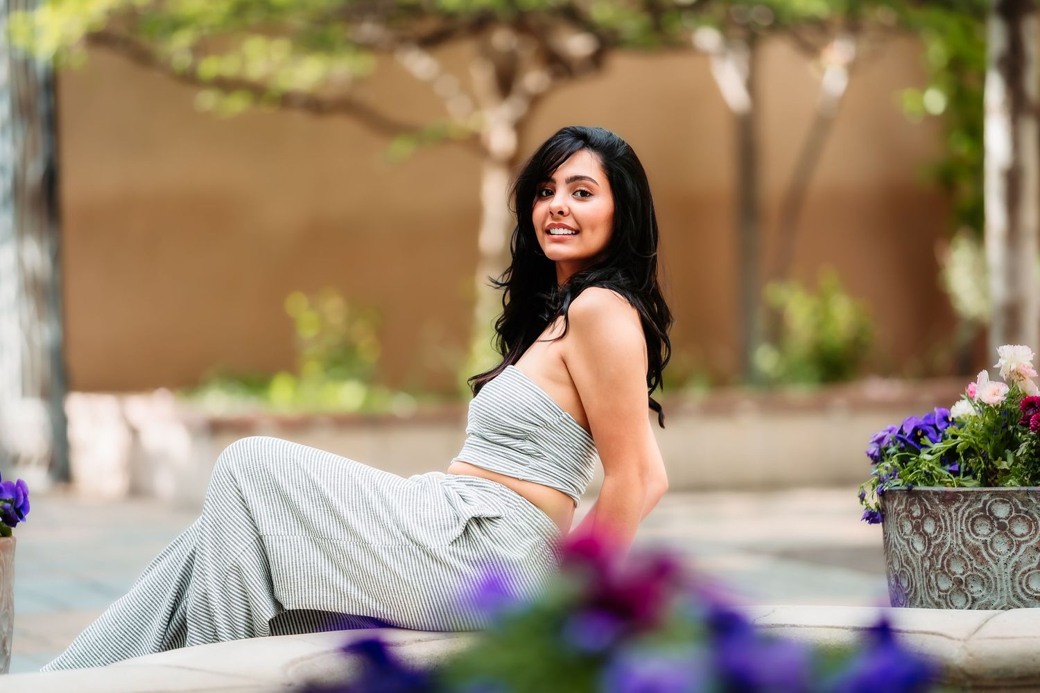 Relaxed outdoor portrait with purple flowers in foreground.