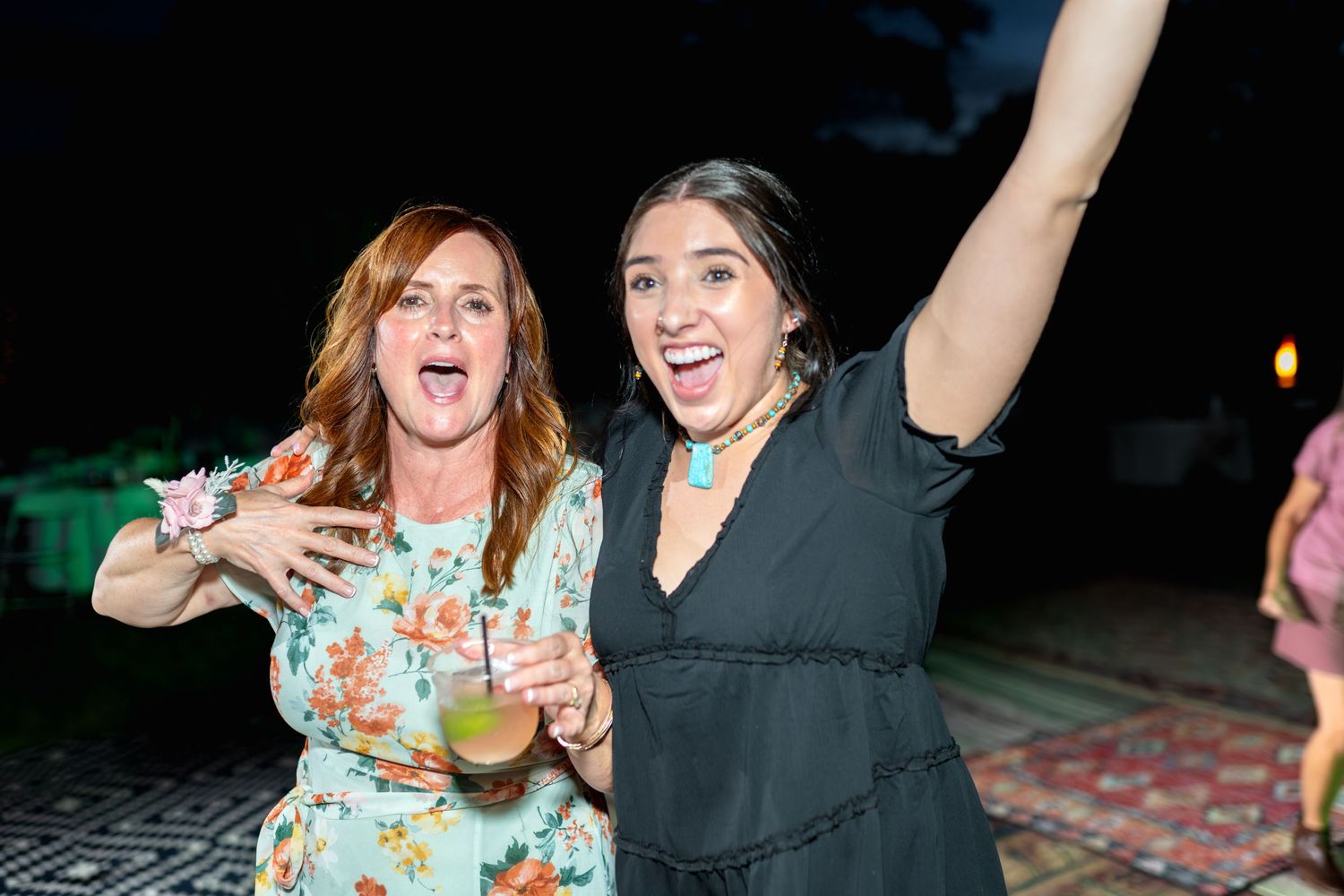 Two wedding guests celebrate enthusiastically on the dance floor at night.