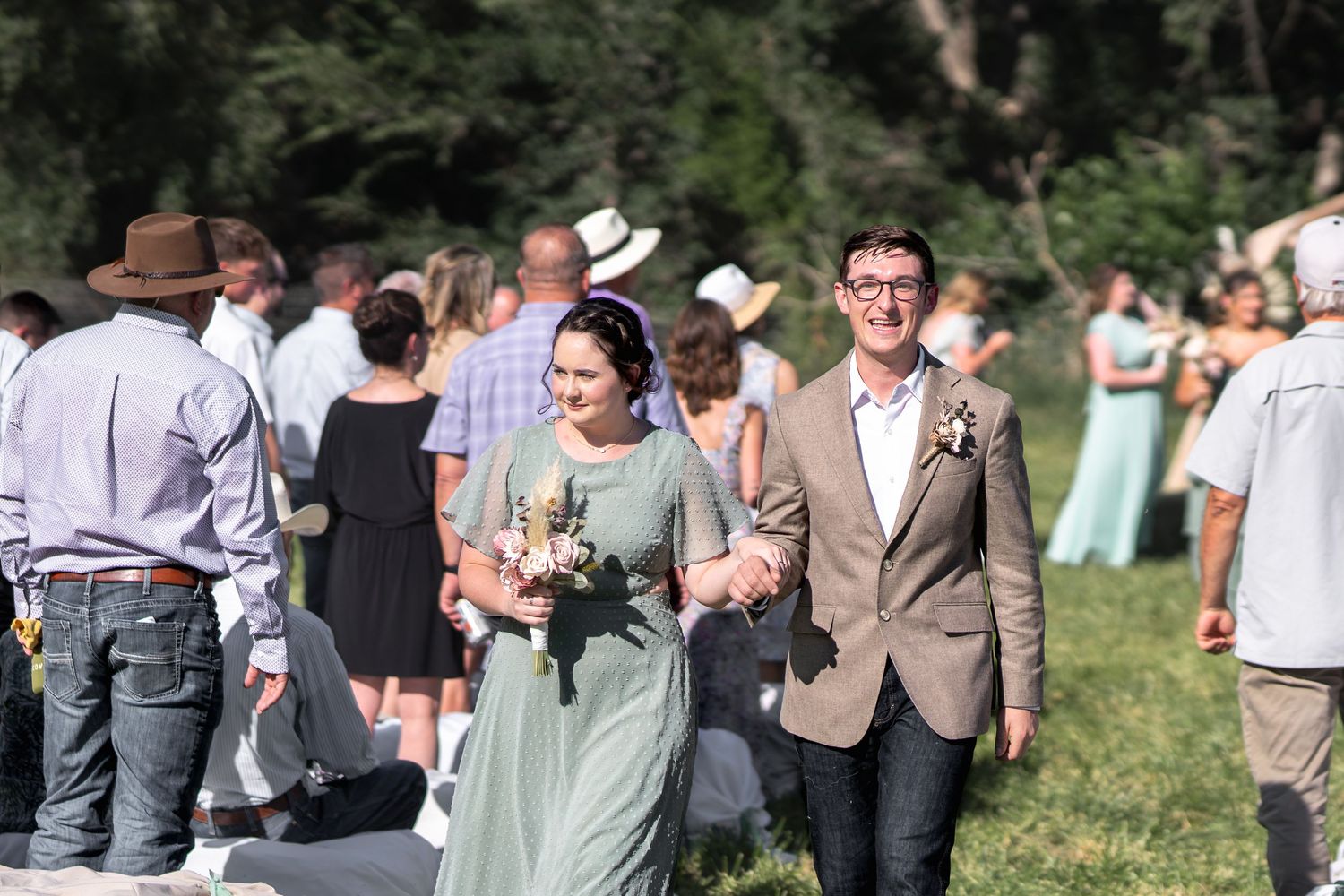 Wedding guests mingle on a grassy lawn during an outdoor reception.