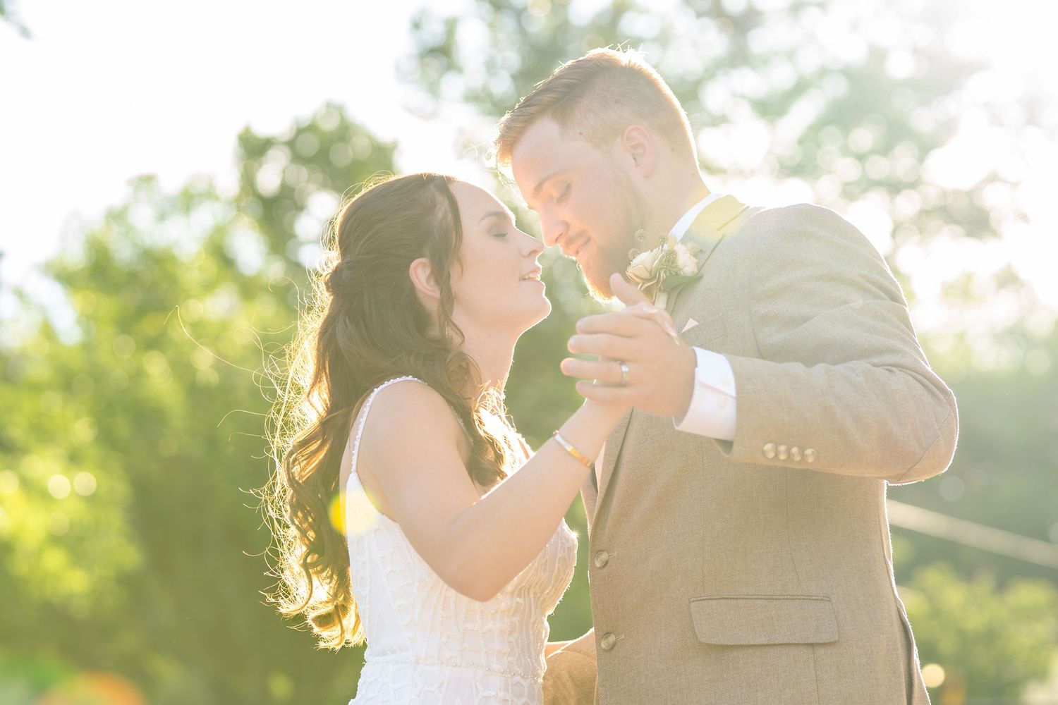 A romantic sunset dance moment captured at an outdoor wedding celebration.