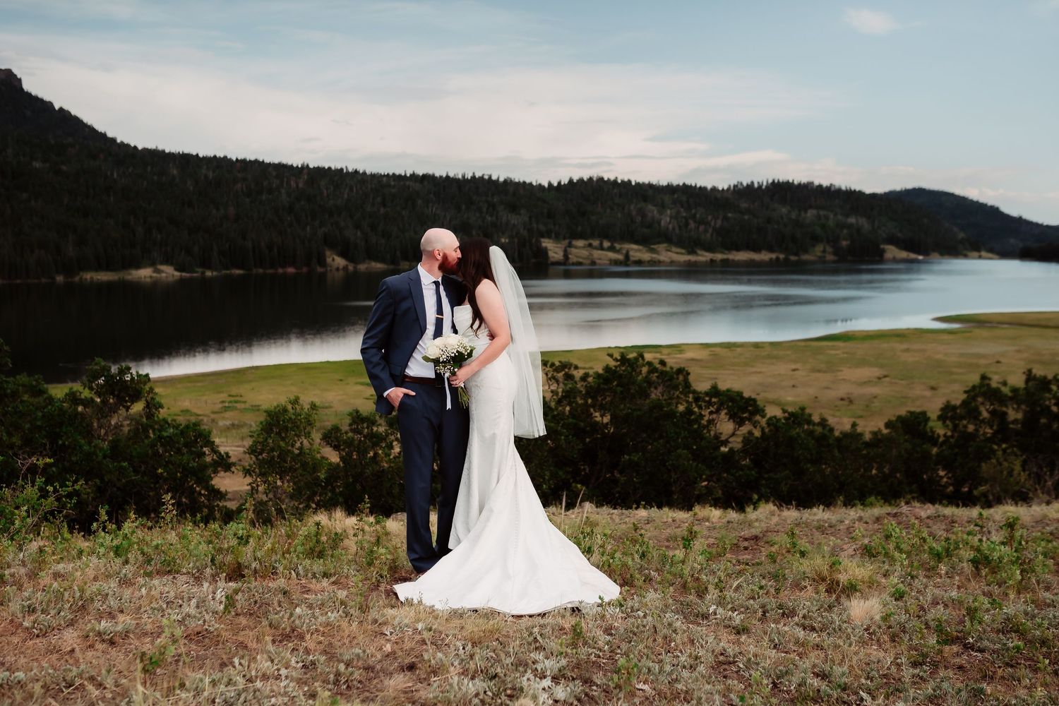 A scenic mountain wedding ceremony overlooking a serene lake with dramatic landscape views.