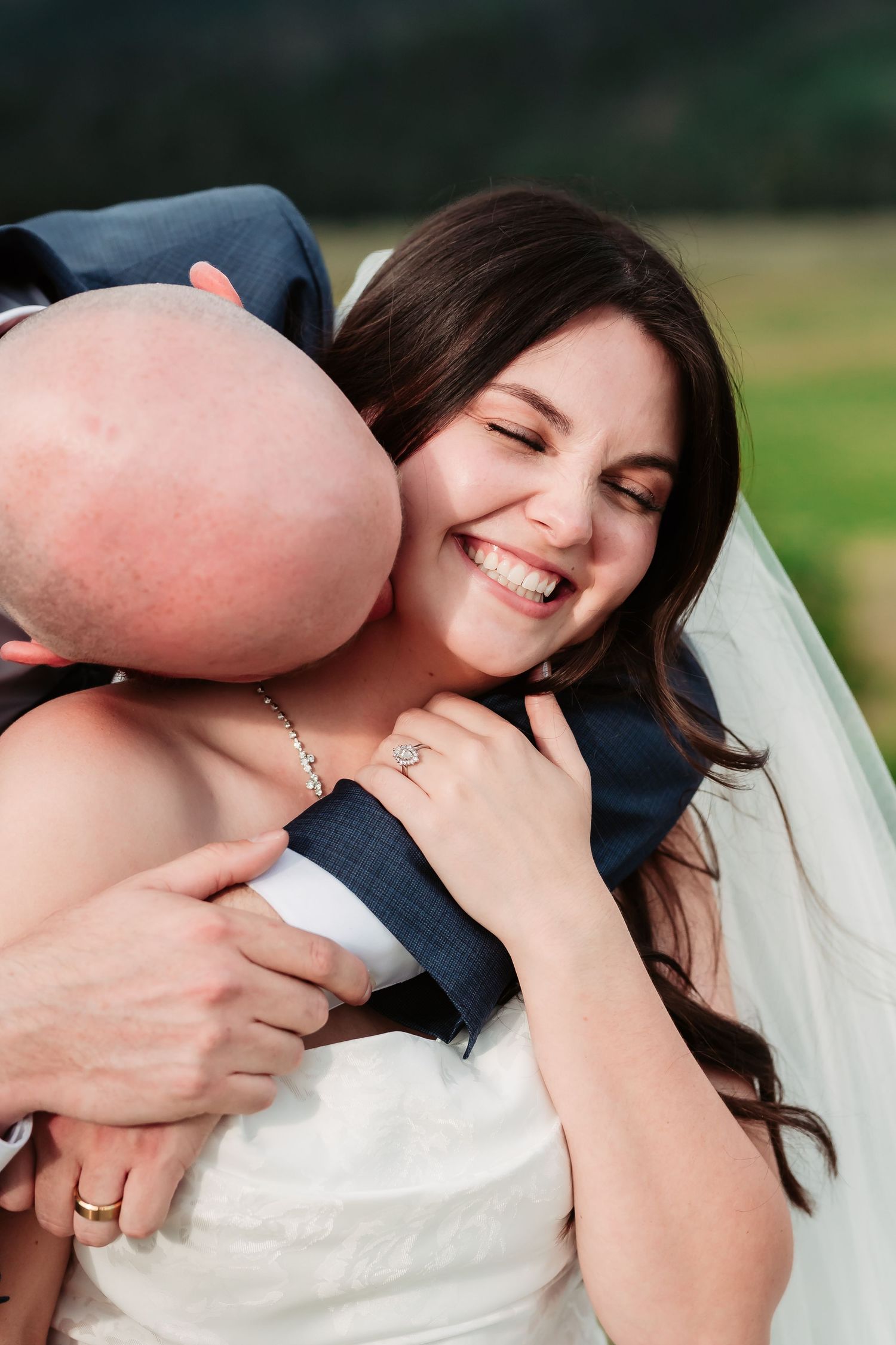Joyful candid wedding moment with white bouquet against mountain landscape.