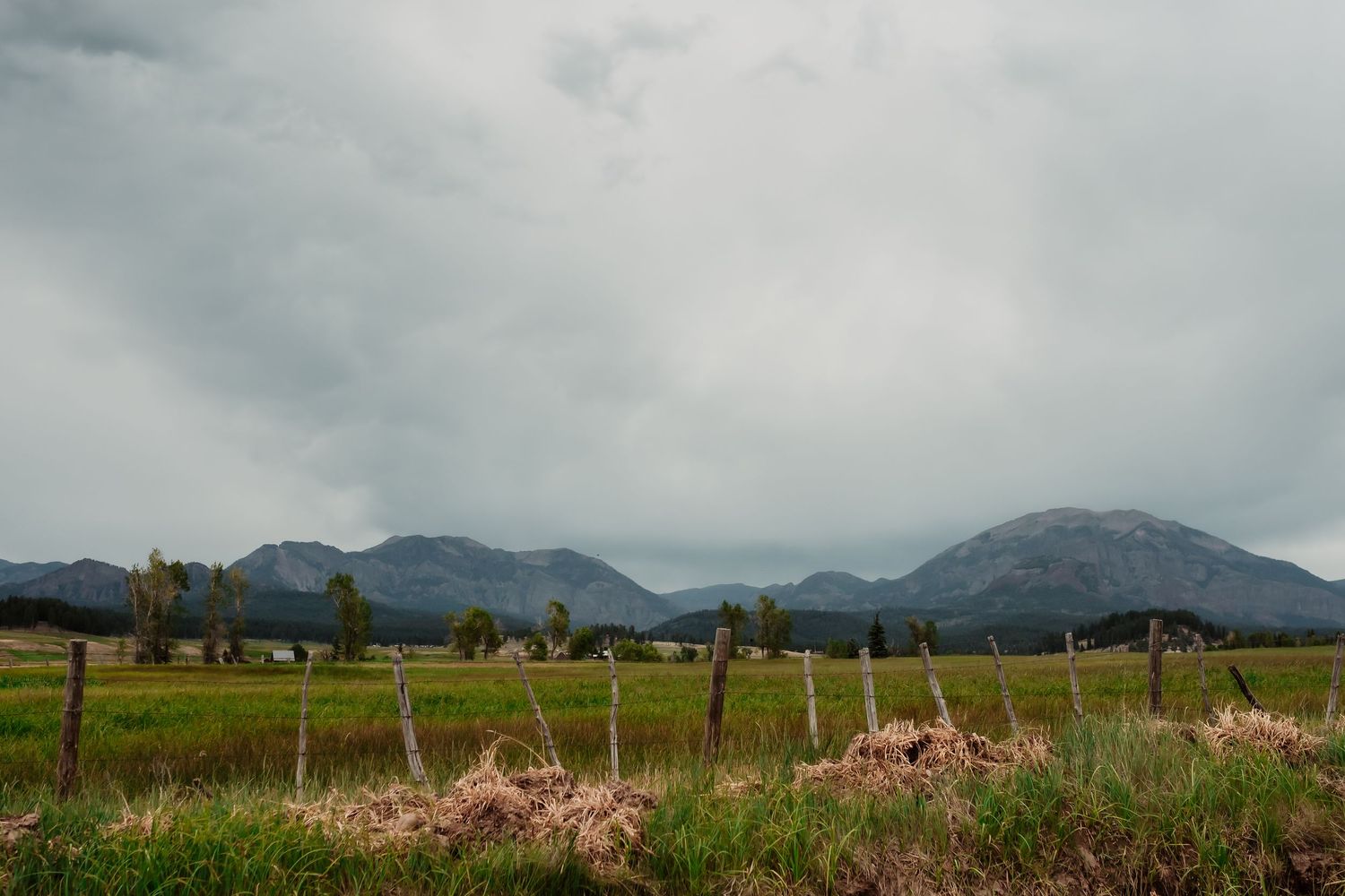 Scenic mountain landscape panorama with rolling hills and dramatic cloudy sky in the distance.