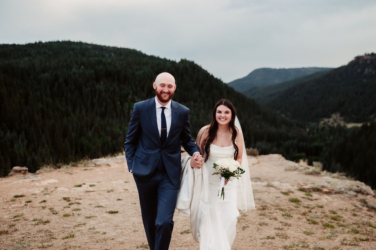 Wedding portraits captured on scenic mountain overlook with dramatic landscape.