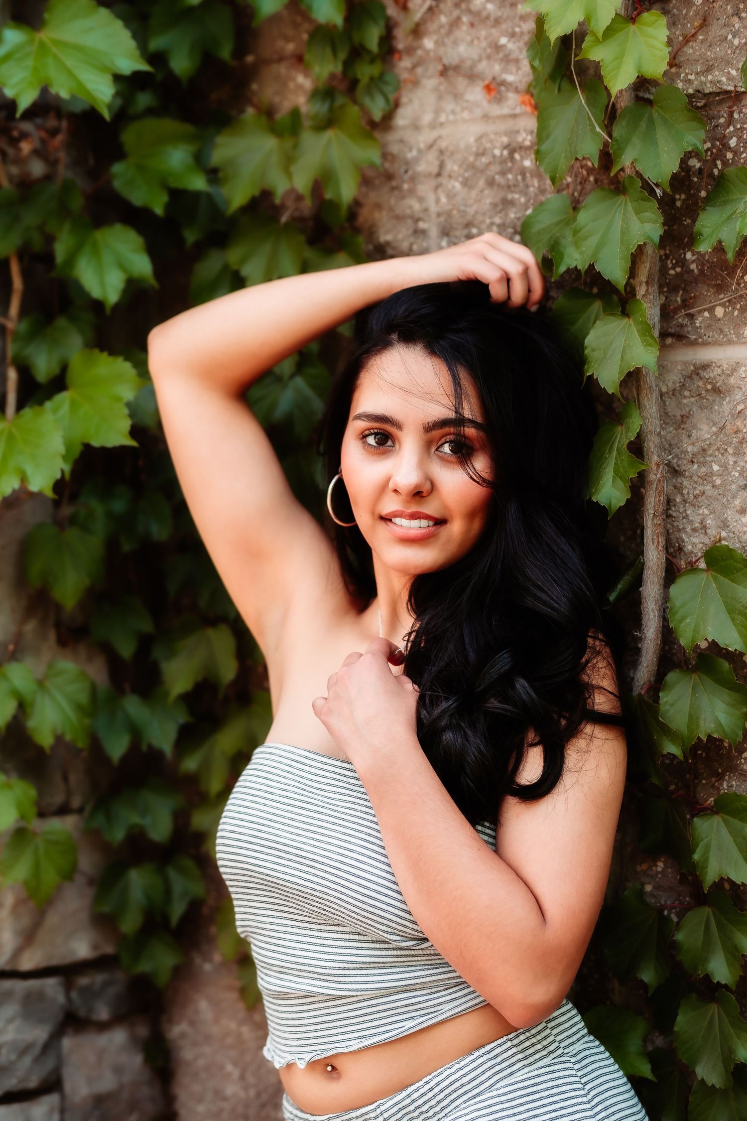 Fashion portrait against a vine-covered wall featuring a striped summer outfit.