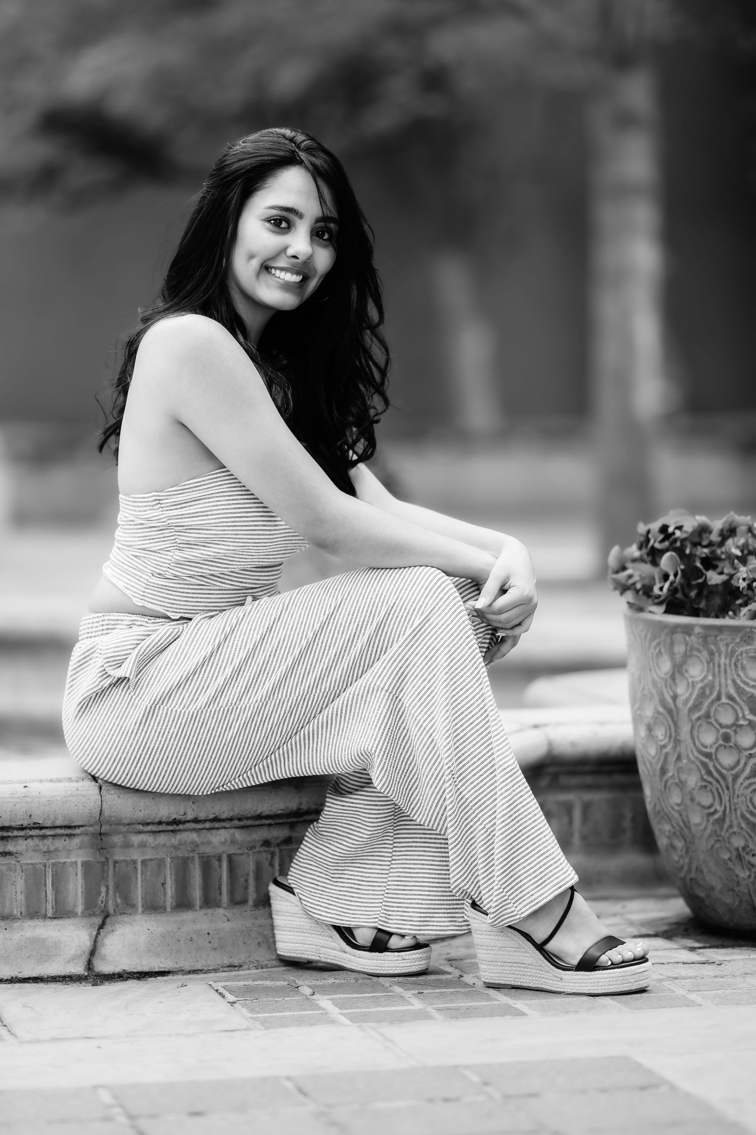 A black and white portrait of someone seated on brick steps wearing casual summer attire.