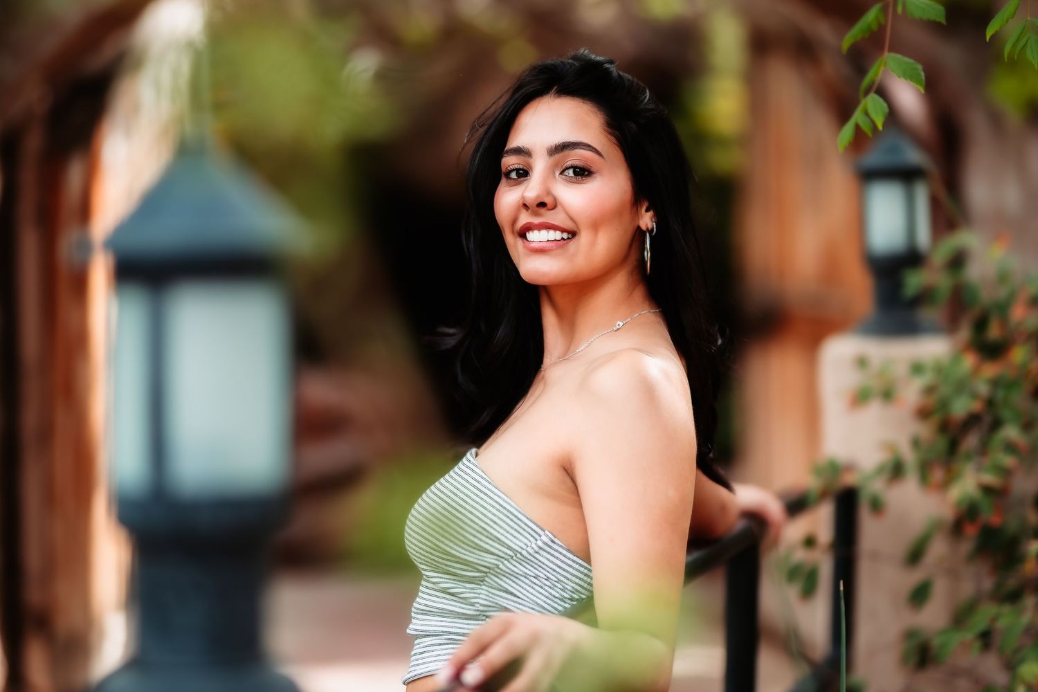A woman in a strapless green dress poses elegantly against a natural outdoor background.