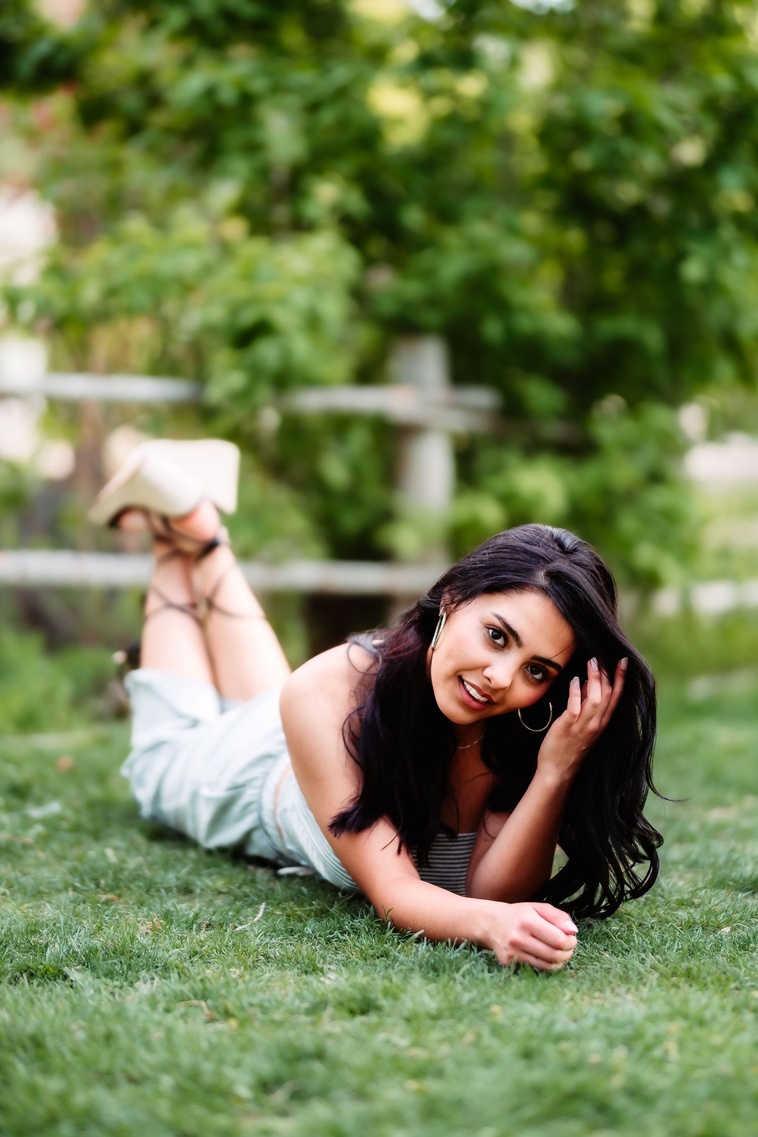 Casual outdoor portrait of someone lying on grass wearing light colored outfit.
