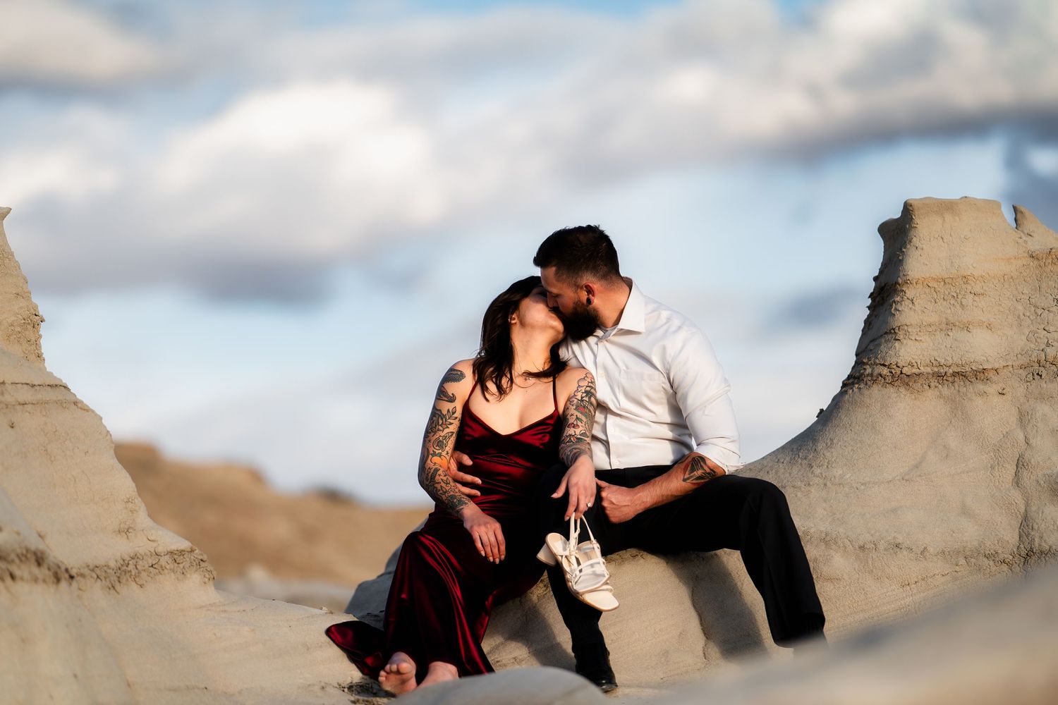 A couple shares an intimate moment while sitting on rocky desert formations.