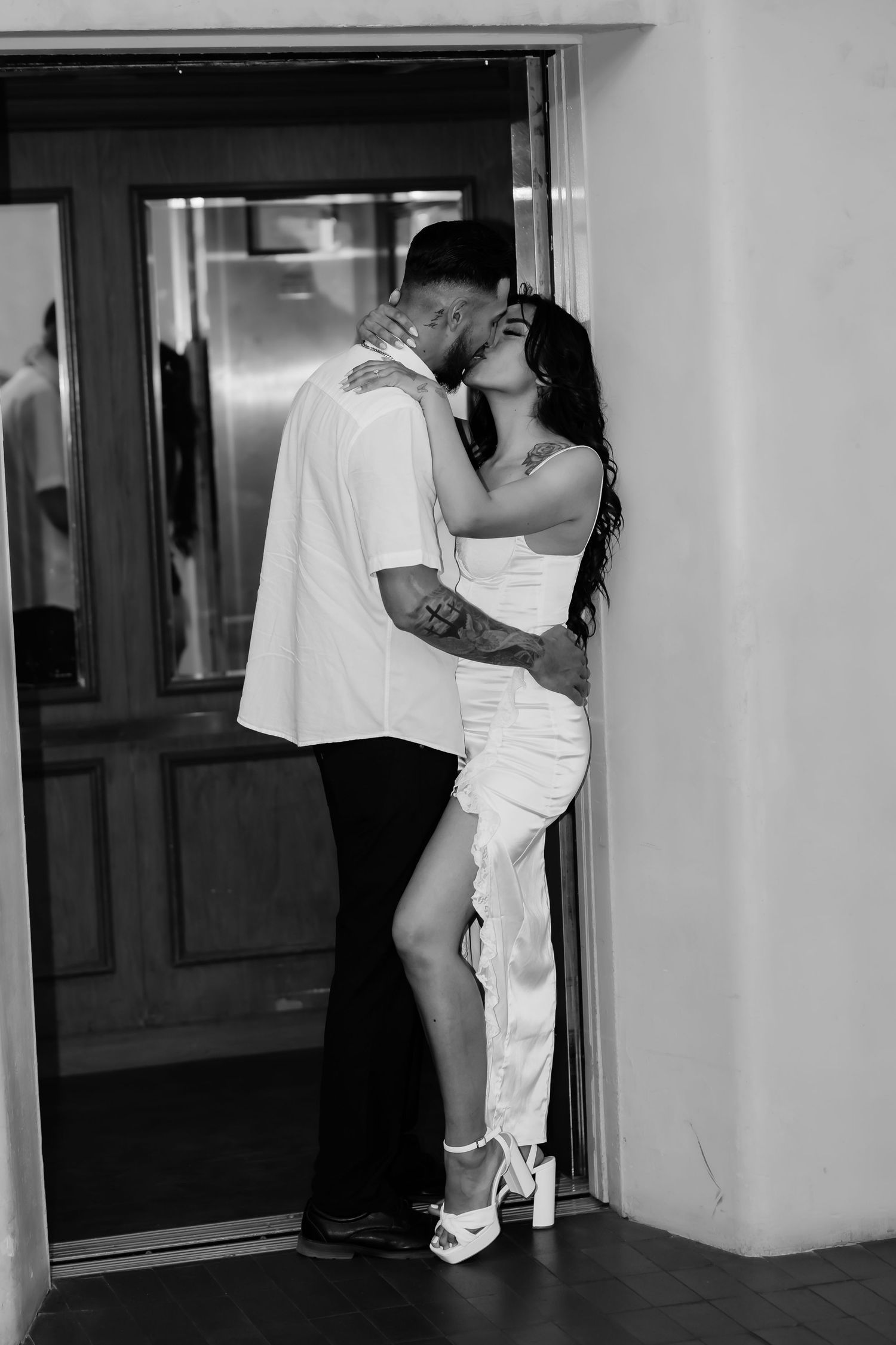 A romantic black and white photo captures an intimate moment by a doorway.