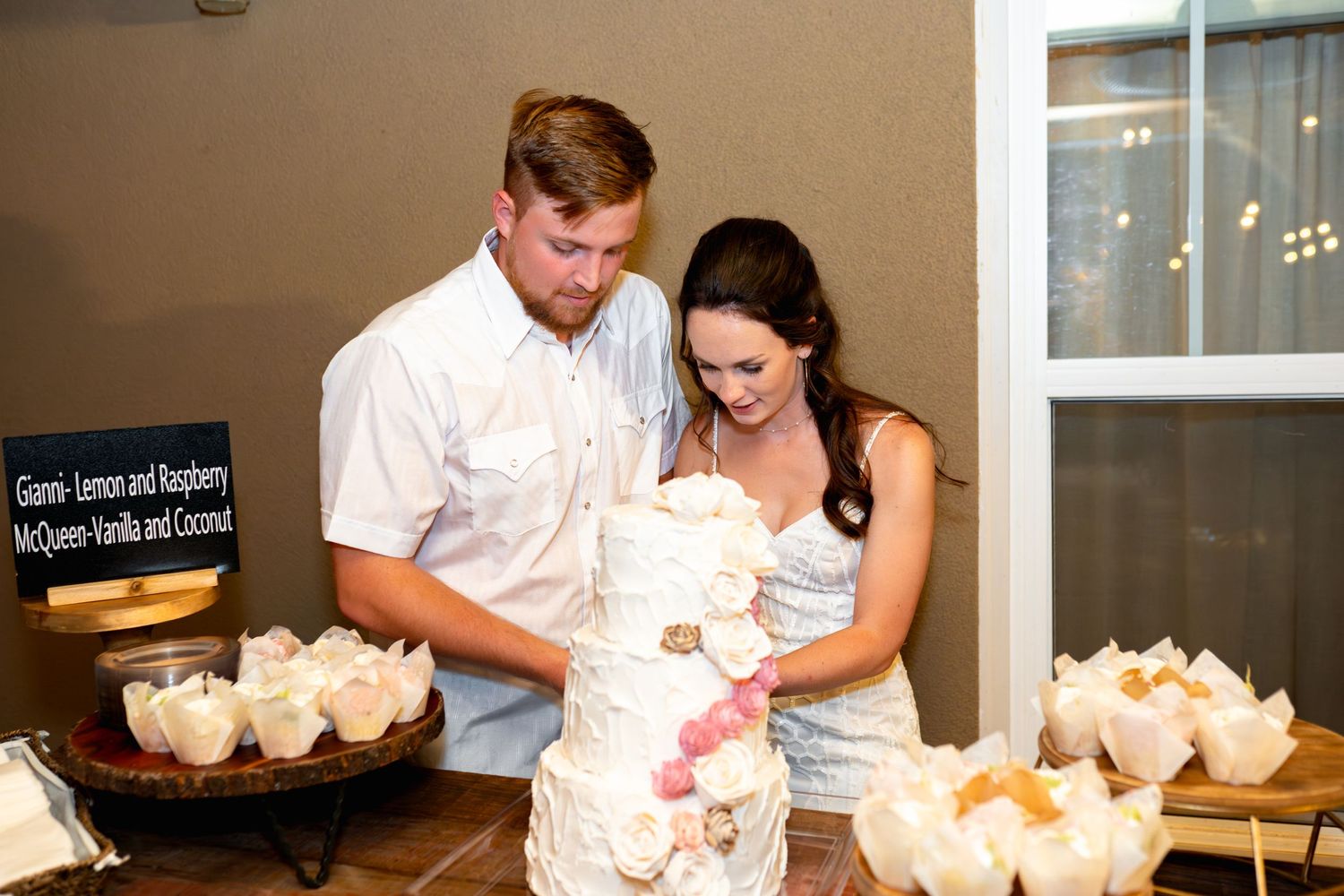 Couple cutting their white wedding cake together at the reception.