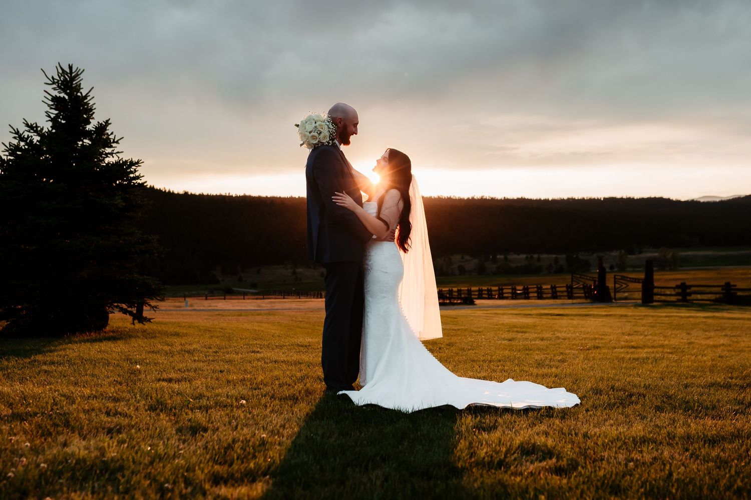 A romantic sunset silhouette of newlyweds in a mountain field.
