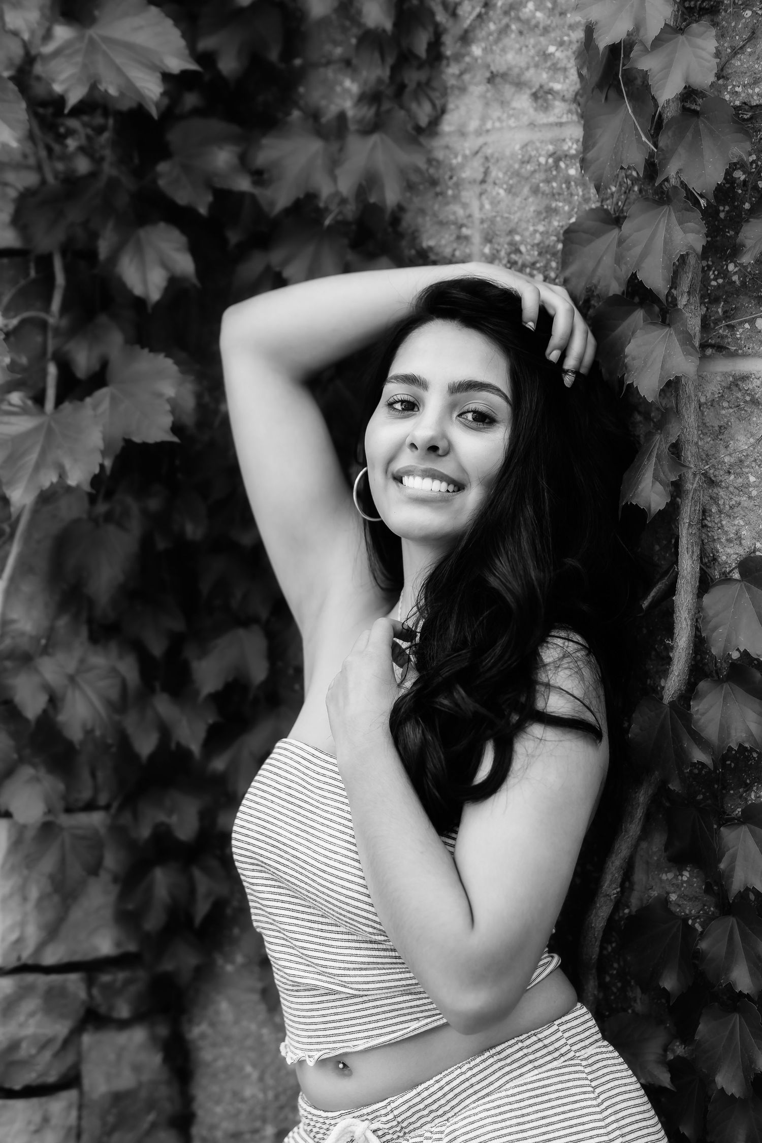 Black and white portrait against wall with ivy leaves showing casual summer style.