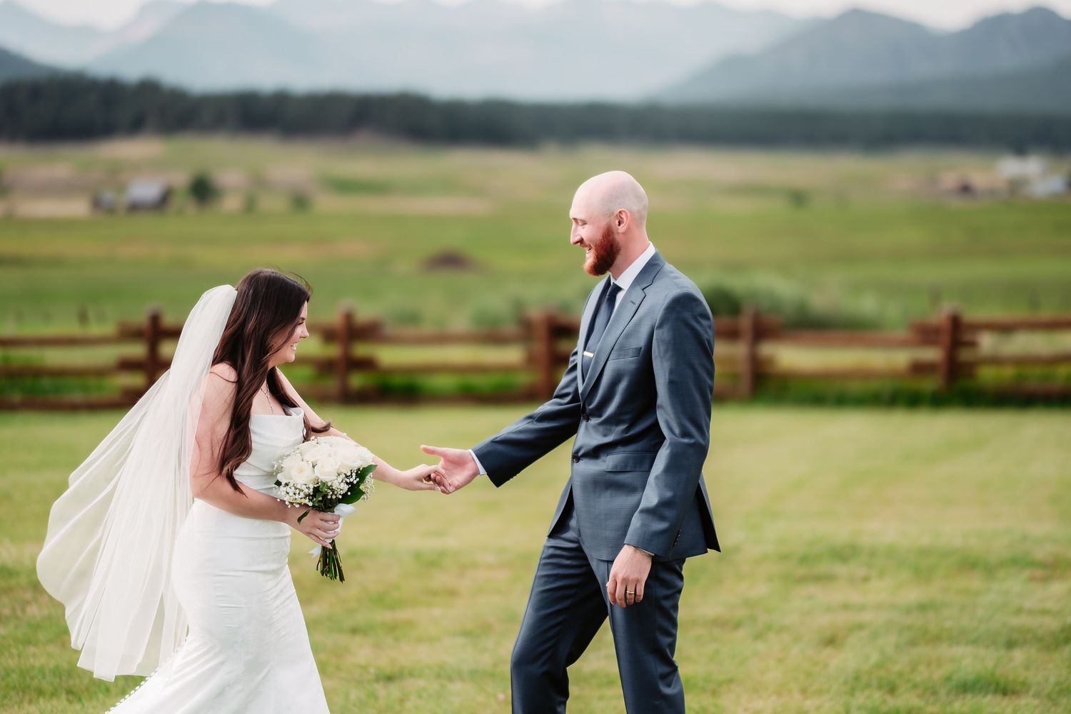 Joyful wedding couple sharing a moment in mountain ranch setting.