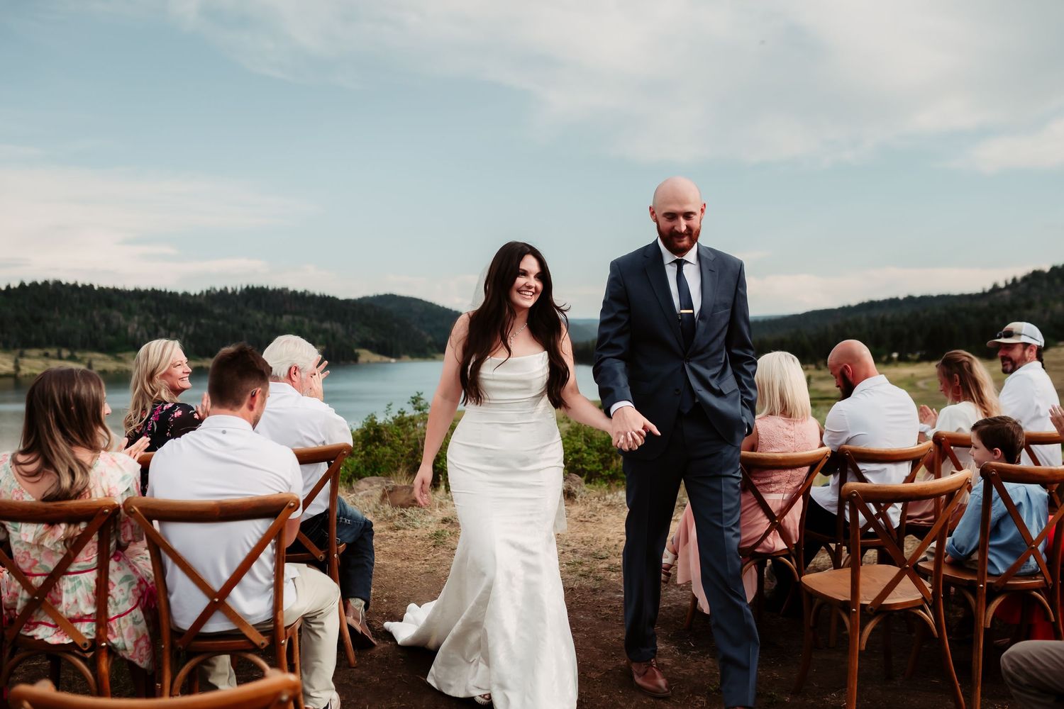 Newlyweds walking back down aisle at outdoor mountain wedding ceremony.