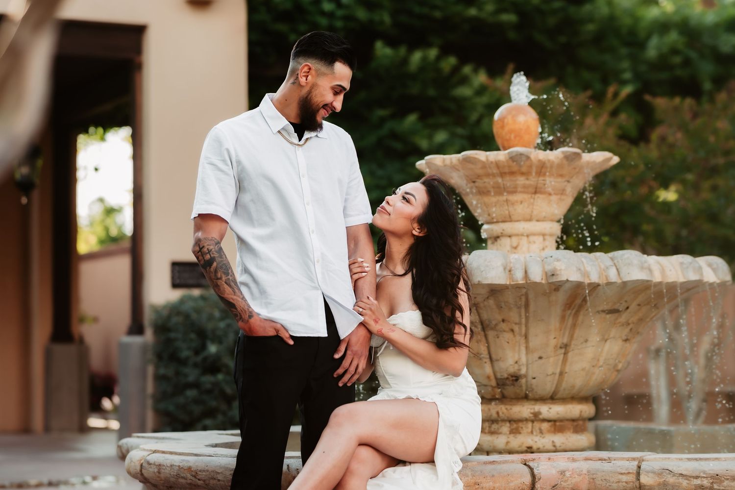 Elegant couple posing by ornate fountain during outdoor portrait session.