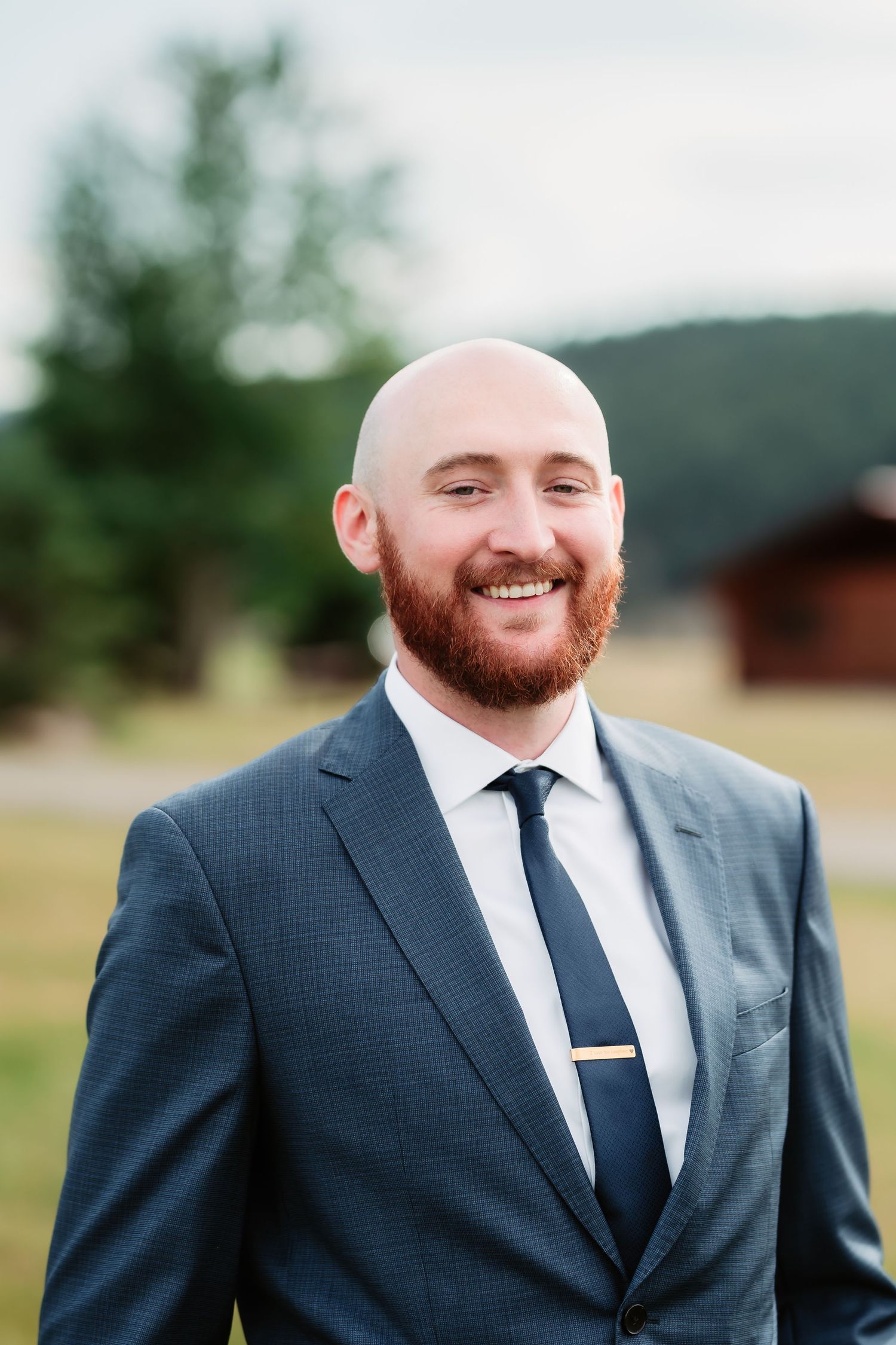 A series of close-up shots showing a groom in a navy suit with a red beard smiling.