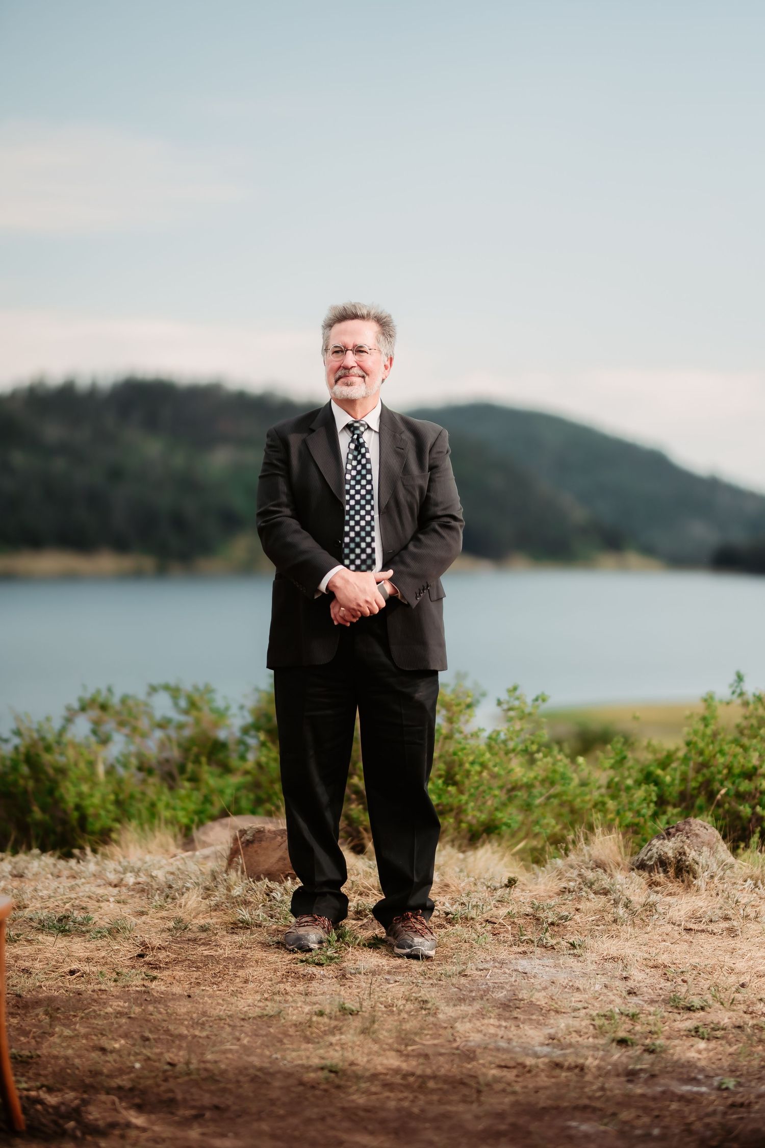 A series of photos showing someone wearing a suit and polka dot tie standing on a scenic hillside overlooking water.