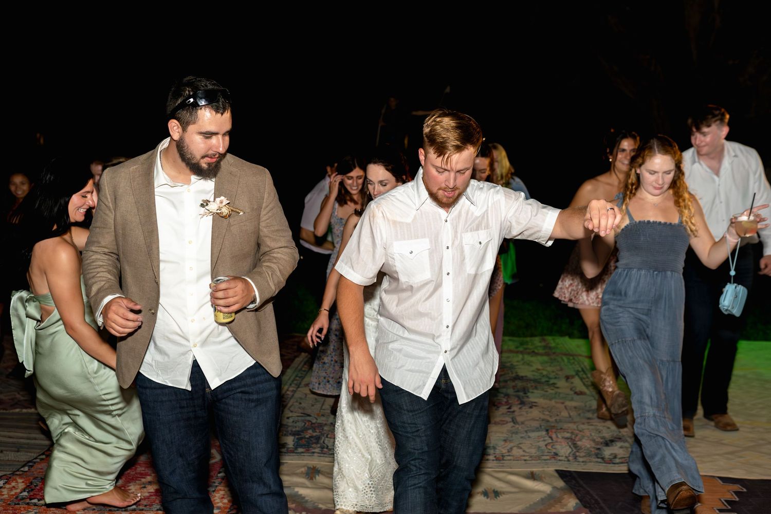 Wedding guests dance together on an outdoor patio during evening reception.