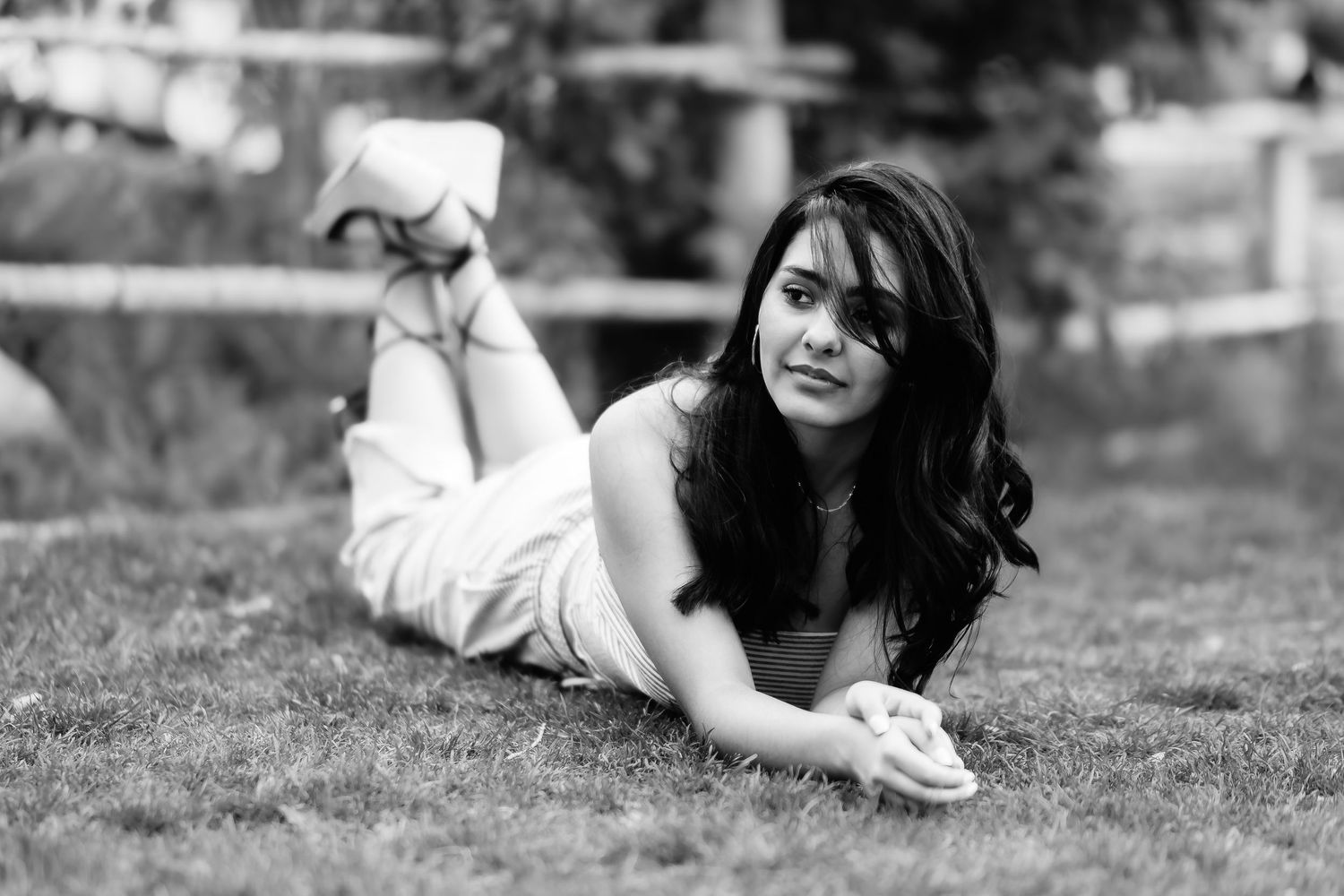 Black and white photo of person lying on grass in relaxed casual pose.