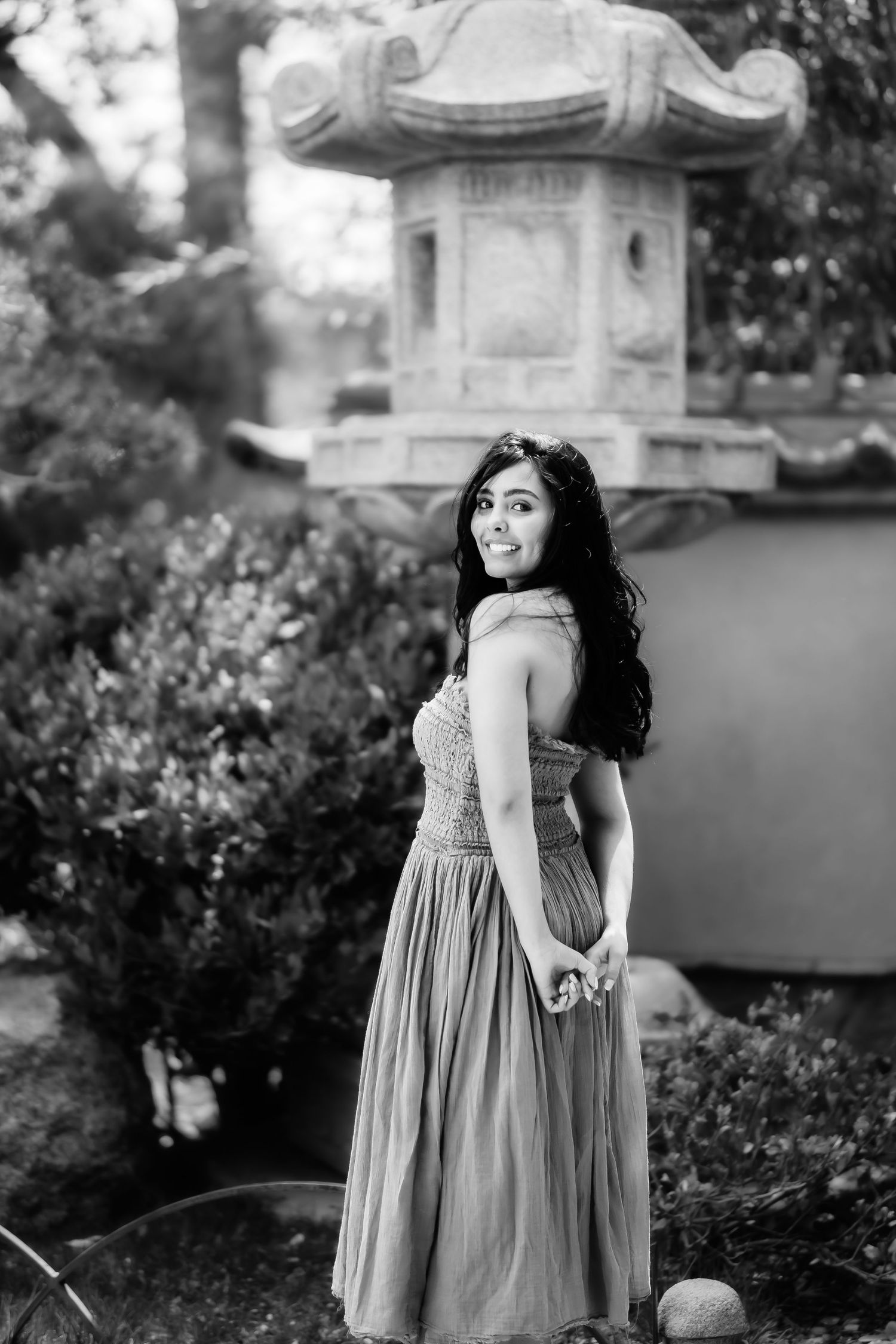 Black and white portrait by an ornate stone lantern in a garden setting.