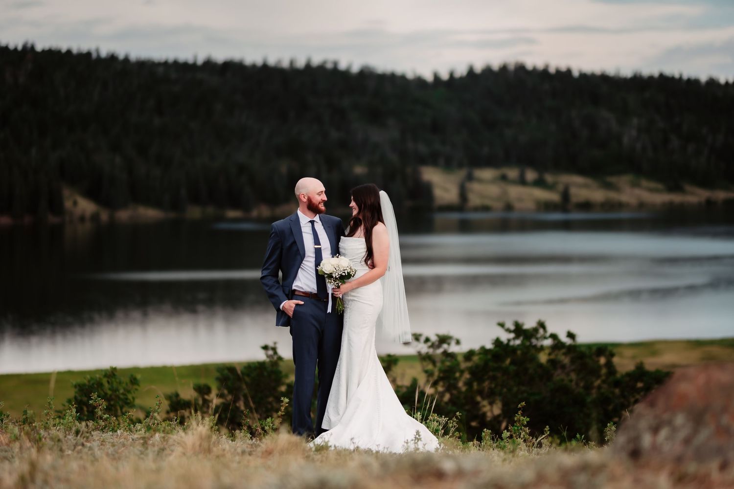 Panoramic wedding photo with lake and forest backdrop during outdoor ceremony.
