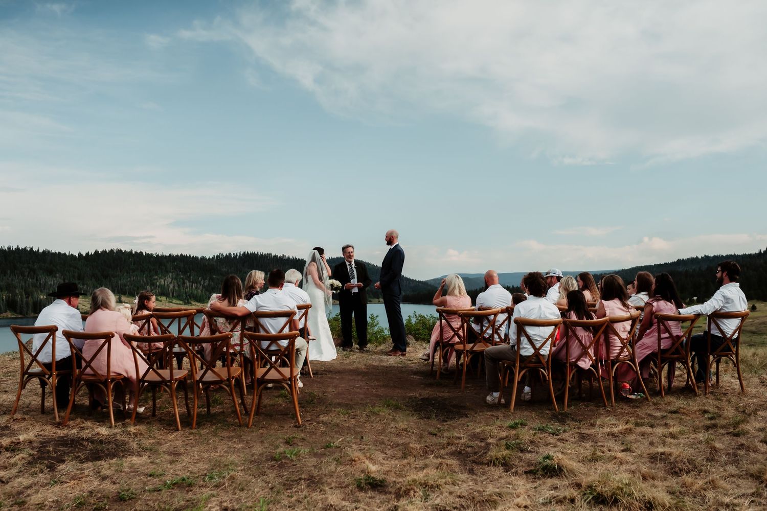 Wooden chairs set up for outdoor wedding ceremony with mountain vista in background.