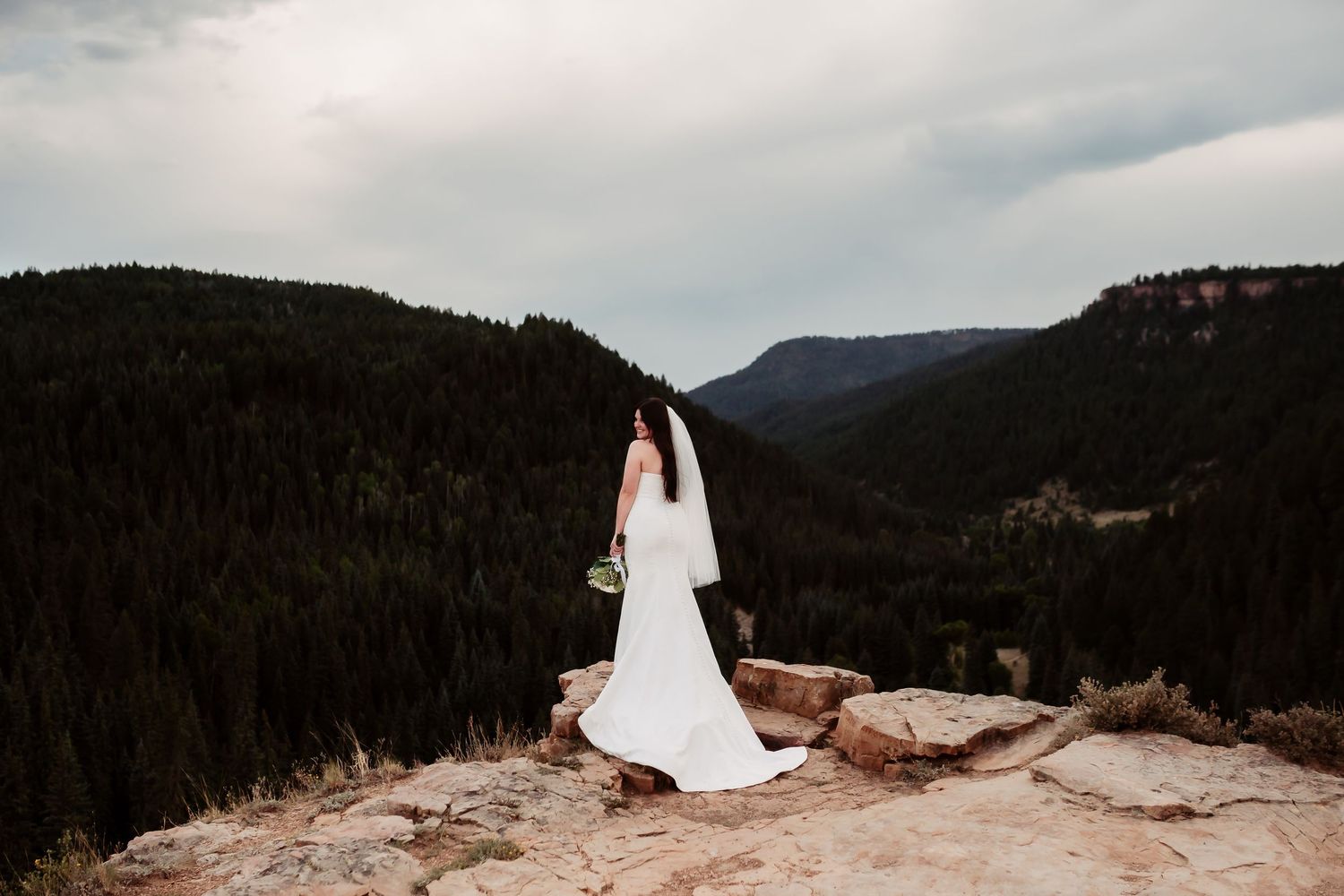Panoramic mountain vista forms backdrop for elegant wedding photography session.