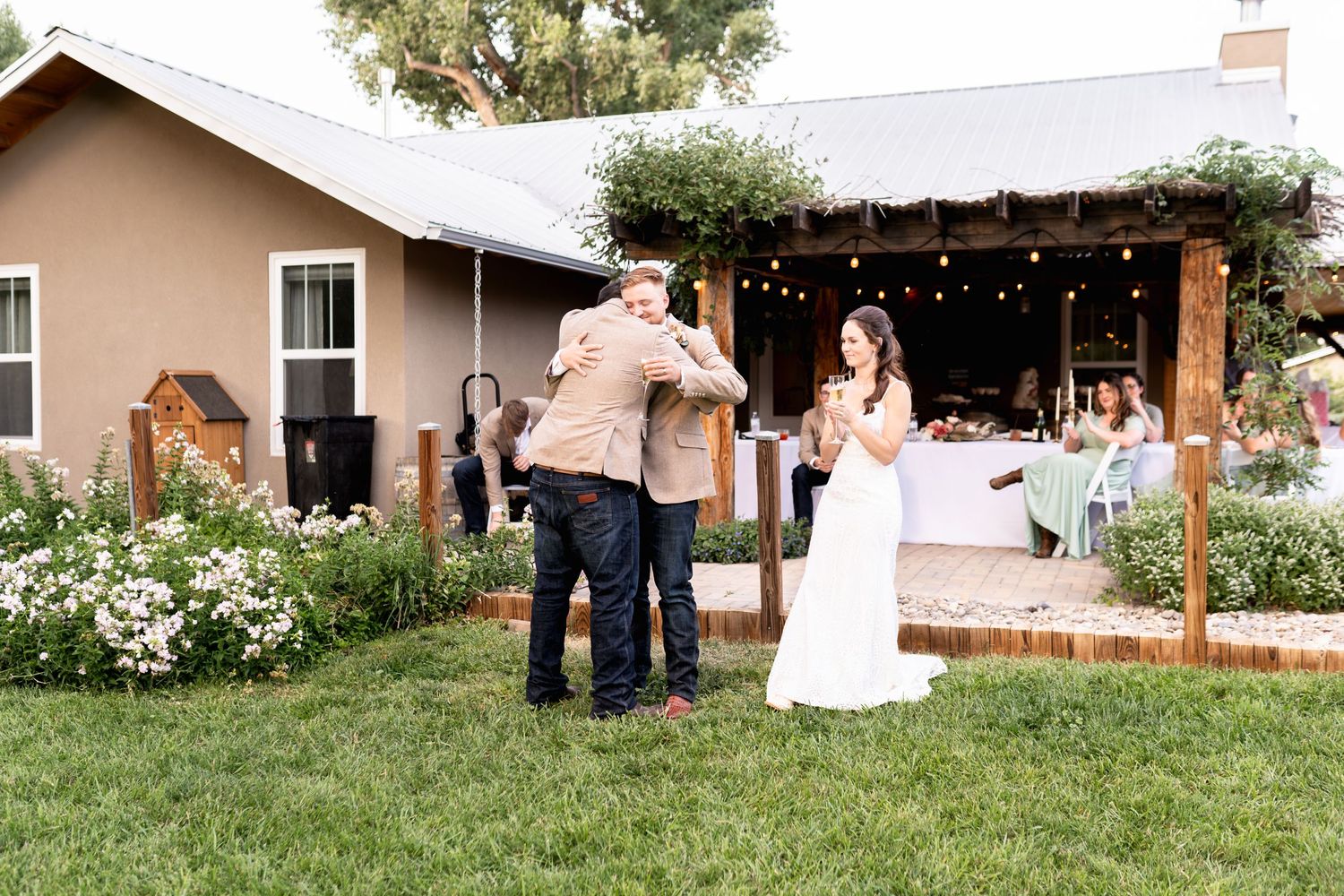 Outdoor wedding reception at a rustic venue with string lights and garden flowers.