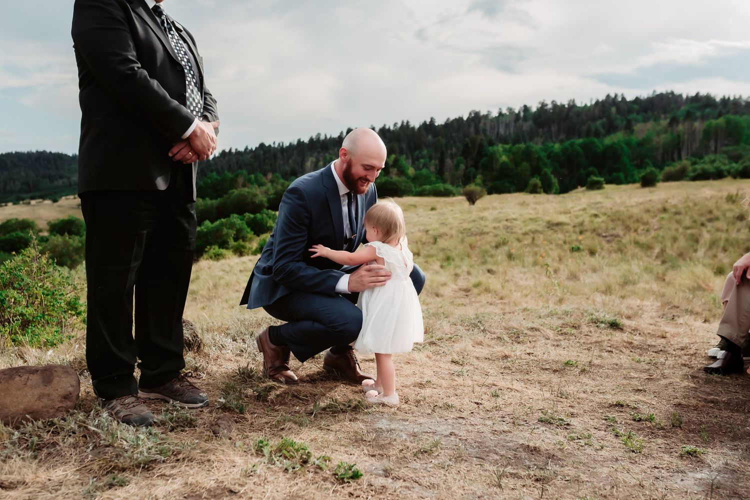 Wedding guests sitting on wooden chairs at an outdoor mountain venue.