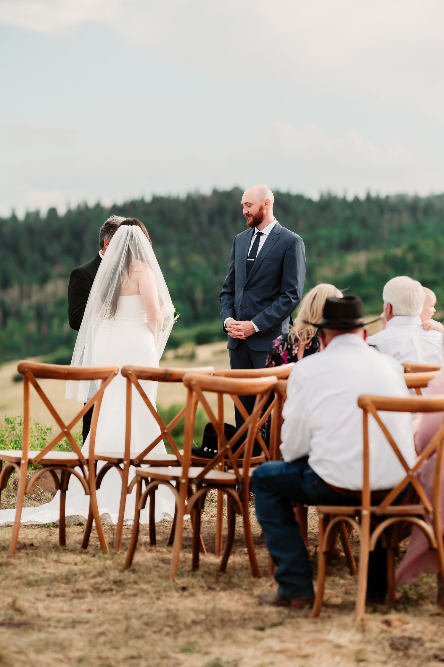 Rustic wooden chairs arranged outdoors for a wedding ceremony with mountain views.